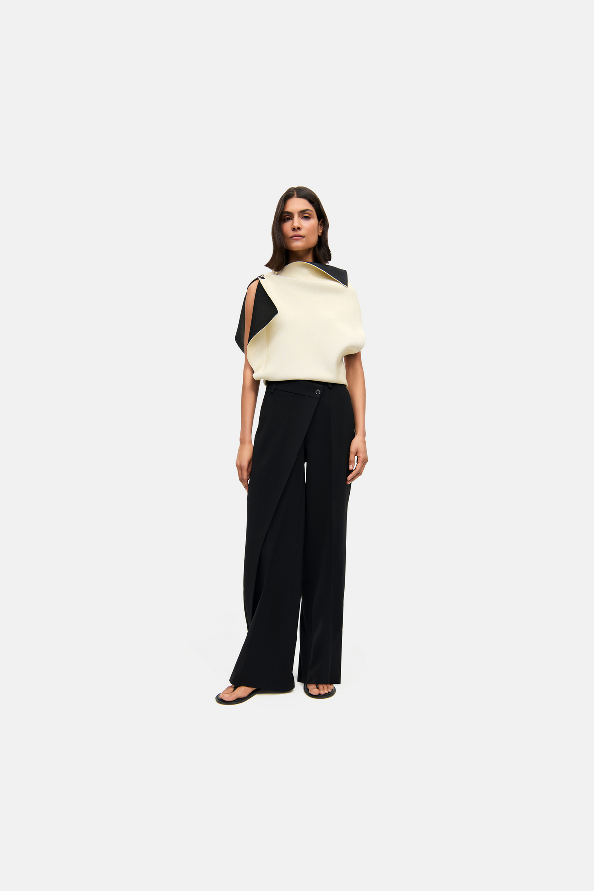 Schwarze Wide Leg Hose aus 90 % Polyester und 10 % Polyurethan, mit asymmetrischem Bund in einem urbanen Umfeld getragen.