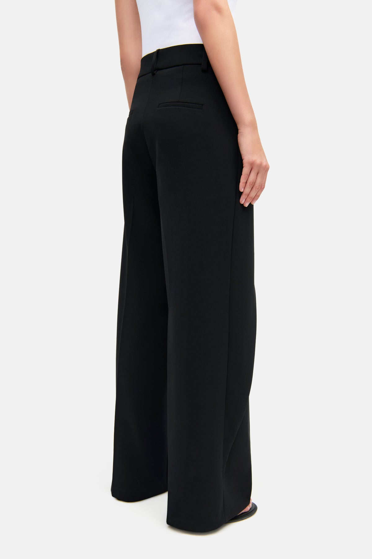 Schwarze, weit geschnittene Hose aus 90% Polyester und 10% Polyurethan, getragen von einer Person in einem neutralen, weißen Oberteil.