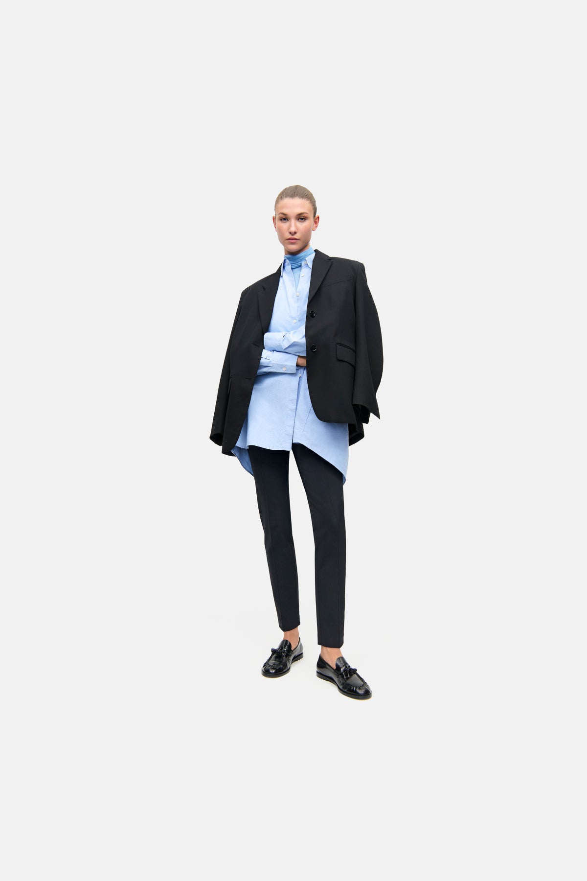 Schwarze, schmal geschnittene Hose aus 88% Polyamid und 12% Elasthan, getragen von einer Person in einem formellen Outfit.