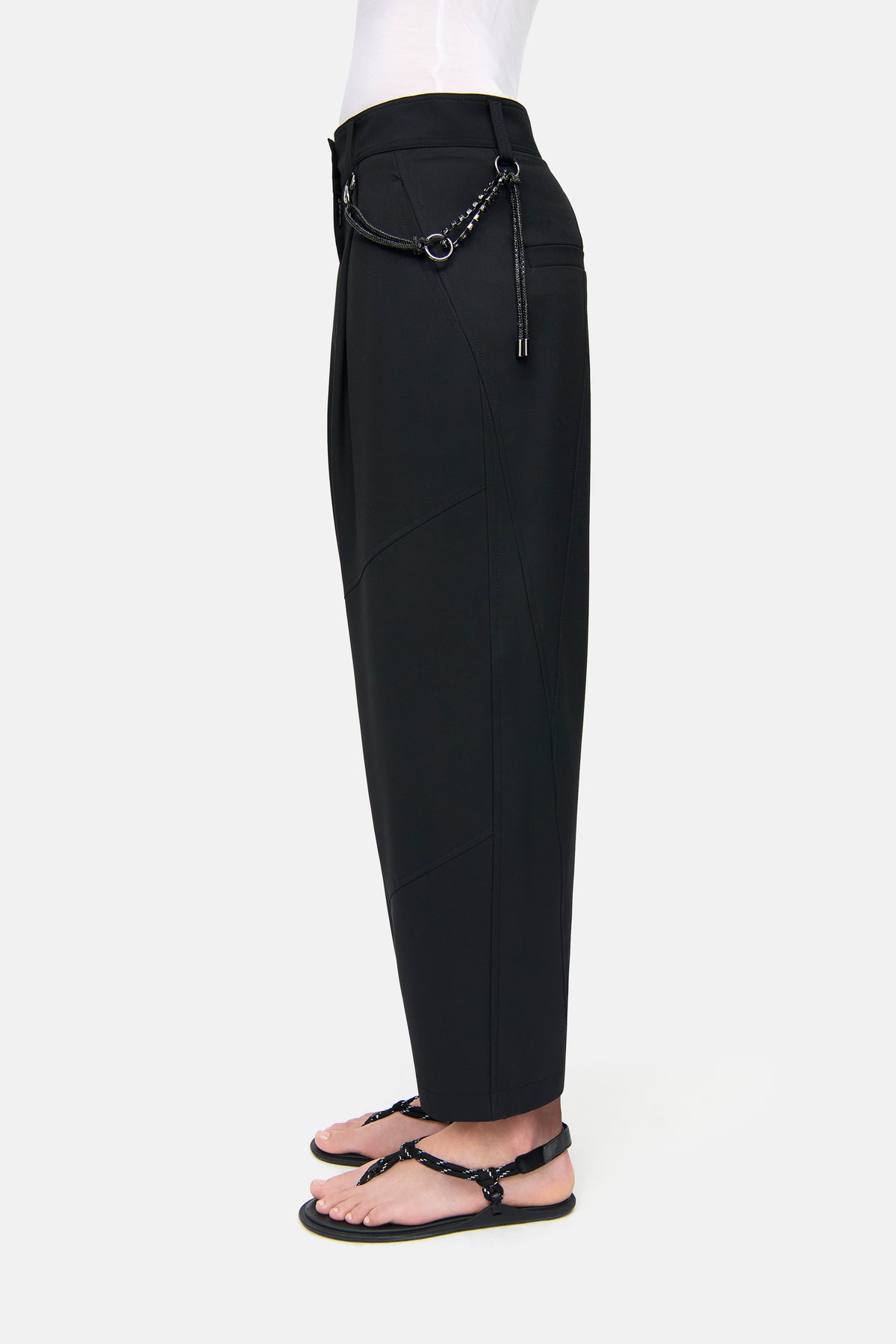 Schwarze O-Shape Hose aus 67% Polyester, 29% Viskose, 4% Elasthan mit abnehmbarer Charivari-Kette, getragen mit Sandalen.