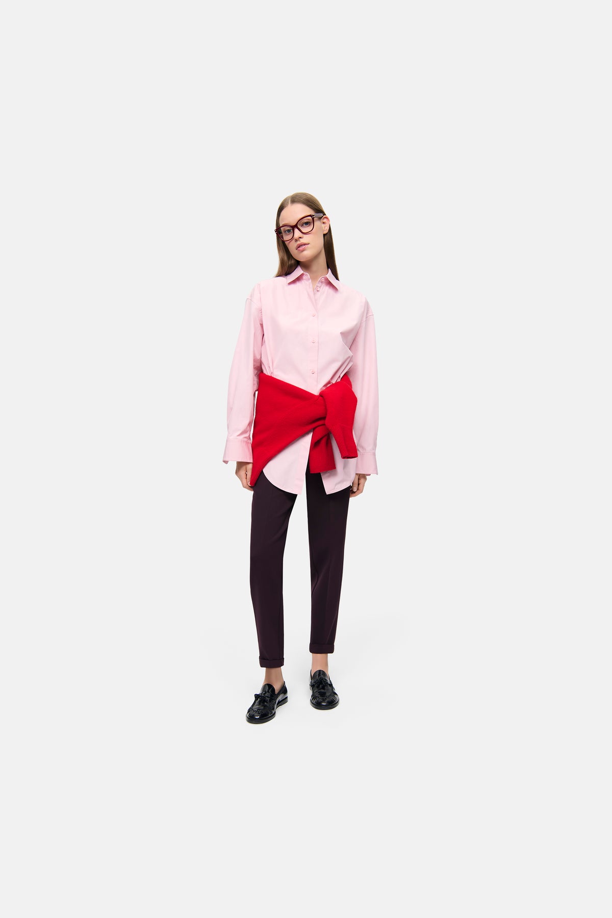 Bordeauxfarbene Karottenhose aus 63% Polyester, 27% Viskose, 7% Baumwolle, 3% Elasthan. Gekürzte Länge, getragen in urbanem Umfeld.