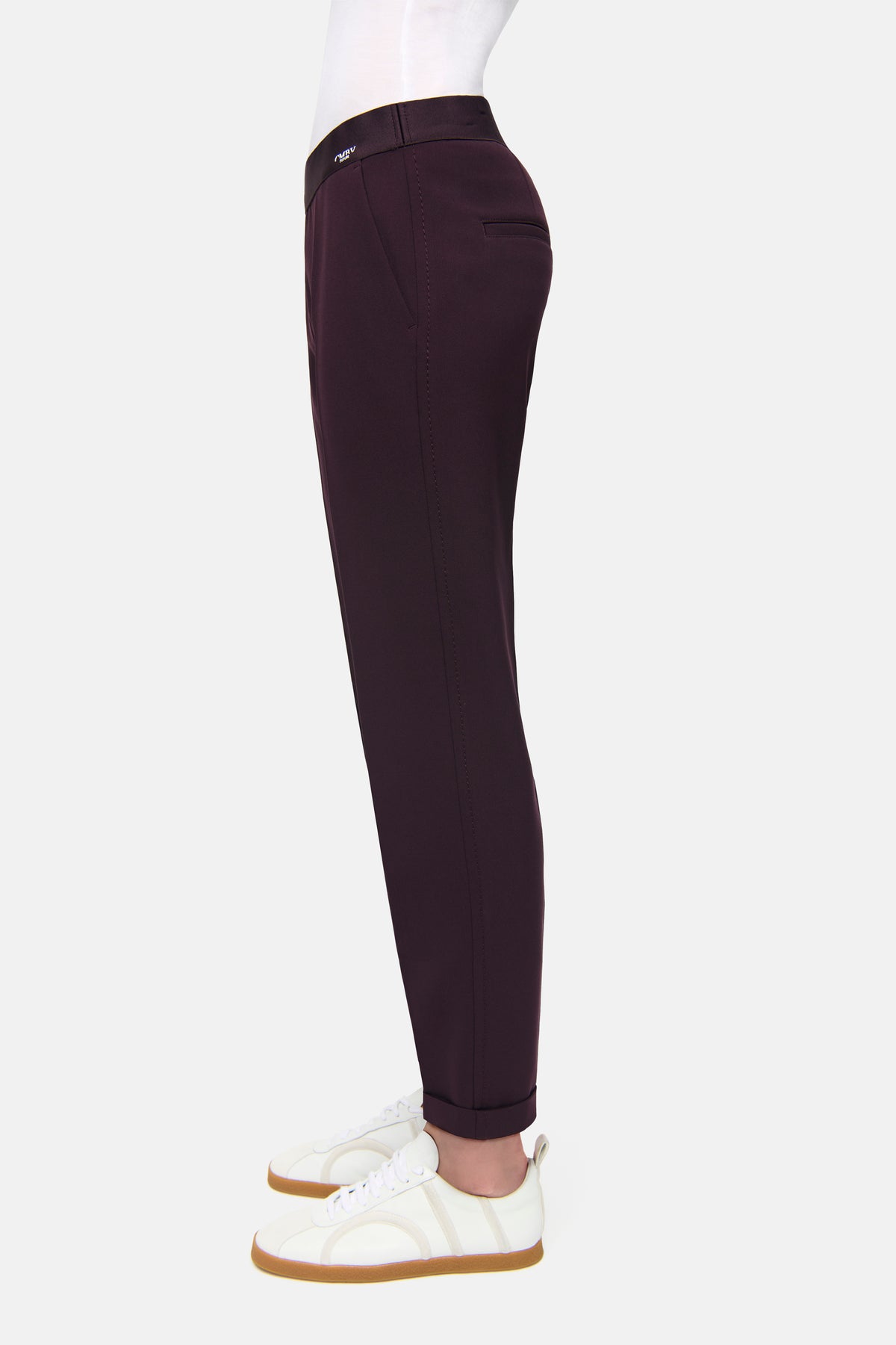 Bordeauxfarbene Karottenhose aus 63% Polyester, 27% Viskose, 7% Baumwolle, 3% Elasthan. Trägerin in Turnschuhen.