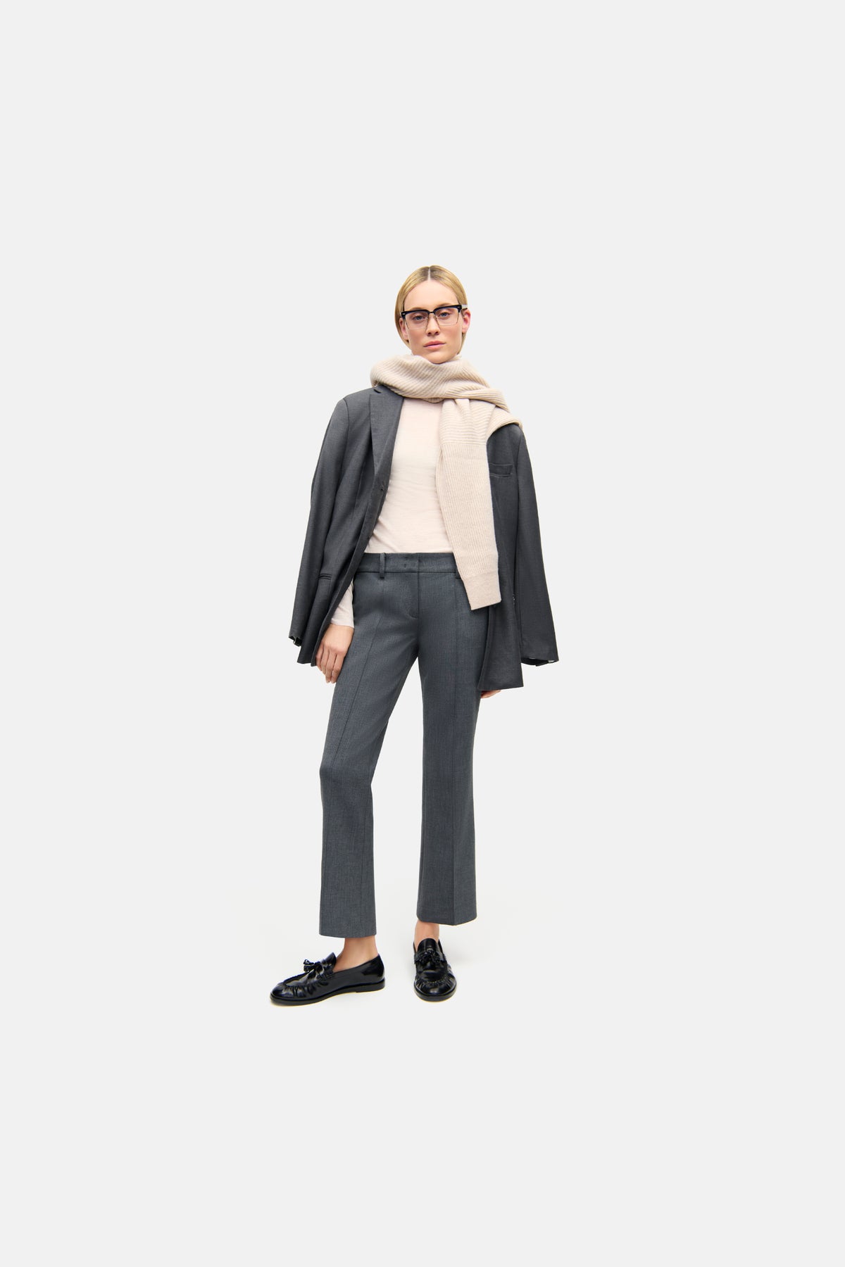 Graue, flared-fit, cropped Hose aus 63 % Polyester, 27 % Viskose, 7 % Baumwolle und 3 % Elasthan. Getragen von einer Person im Büro-Outfit.