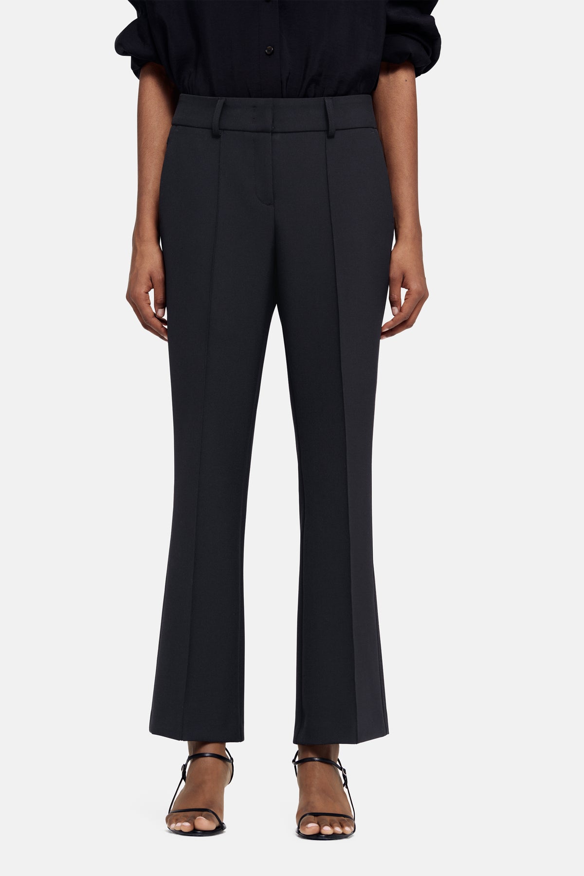 Dunkelblaue Flared-Hose aus 63 % Polyester, 27 % Viskose, 7 % Baumwolle und 3 % Elasthan. Getragen in einem formellen Setting.