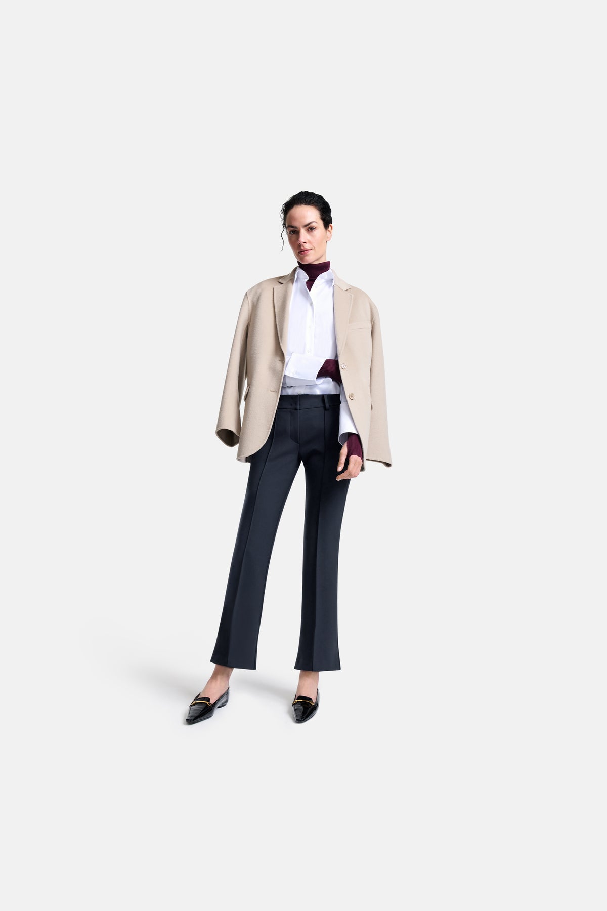 Dunkelblaue Flared-Hose aus 63% Polyester, 27% Viskose, 7% Baumwolle, 3% Elasthan, getragen in einem formellen Outfit mit Blazer.