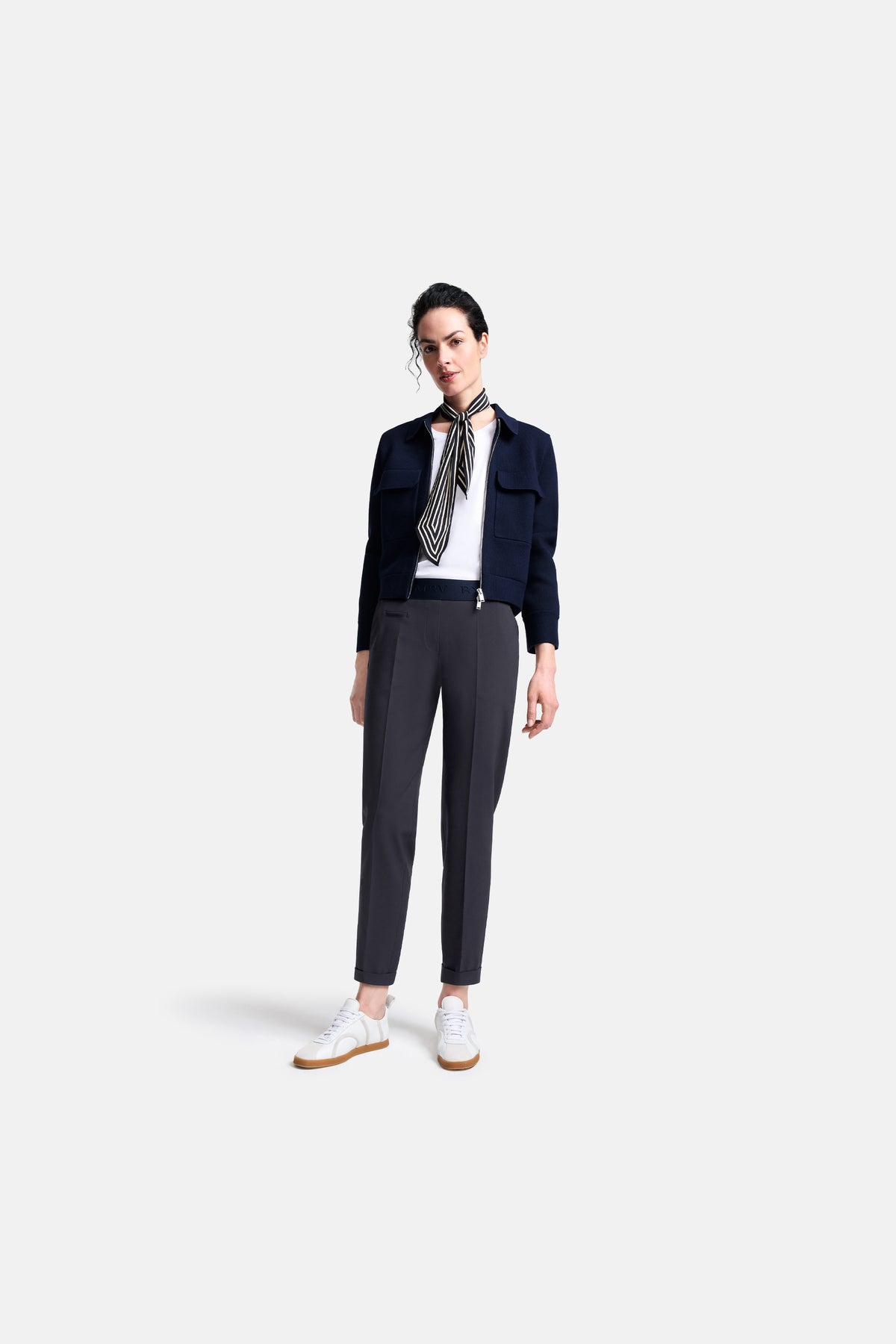 Dunkelgraue Karottenhose aus 67% Polyester, 29% Viskose, 4% Elasthan, getragen von einer Person. Eleganter urbaner Stil.