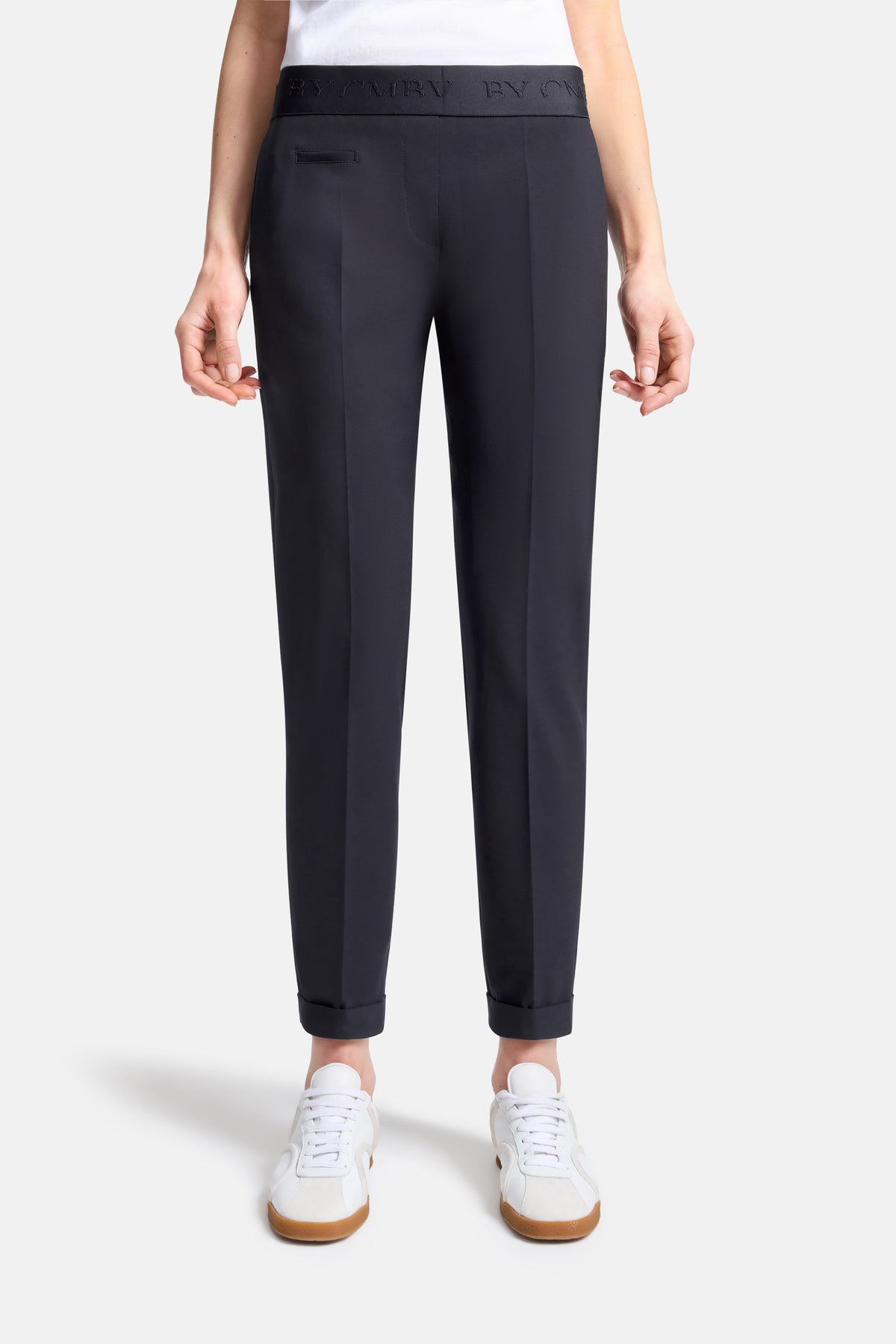 Dunkelblaue Karottenhose aus 67% Polyester, 29% Viskose, 4% Elasthan, mit elastischem Bund. Getragen in einer urbanen Umgebung.