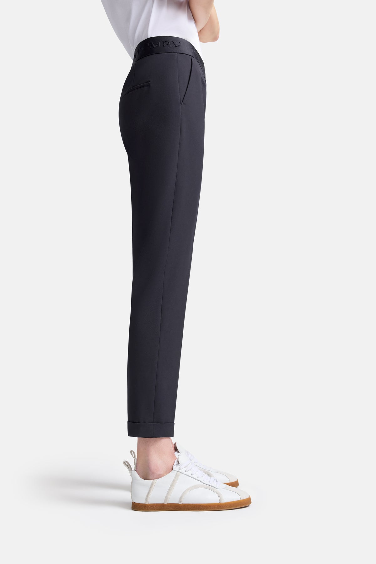 Dunkelblaue, verkürzte Carrot-Fit Hose aus 67% Polyester, 29% Viskose, 4% Elasthan. Getragen mit weißen Turnschuhen.