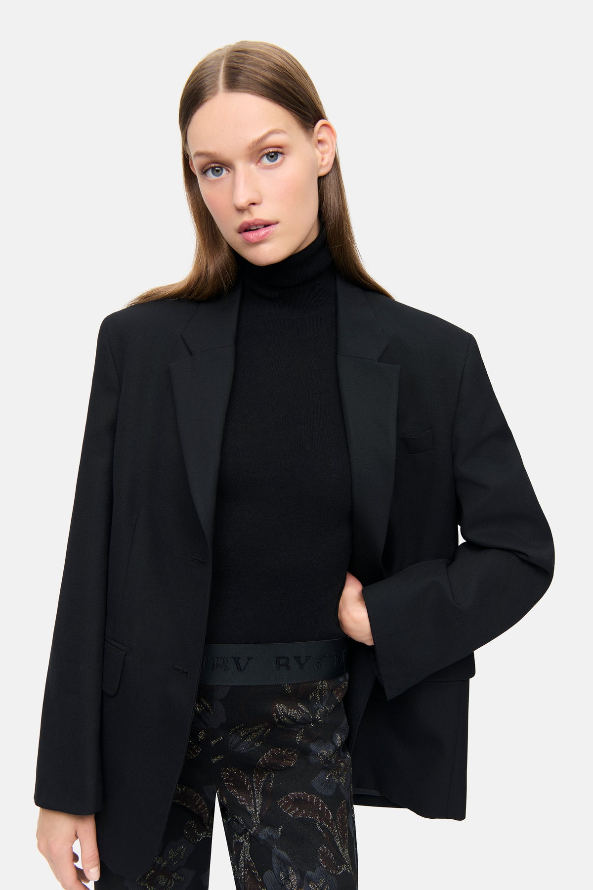 Schwarze Flared-Hose aus Blumen Lurex Jersey Jacquard, mit gedeckten Blau- und Brauntönen, getragen von einer Frau in eleganter Kleidung.