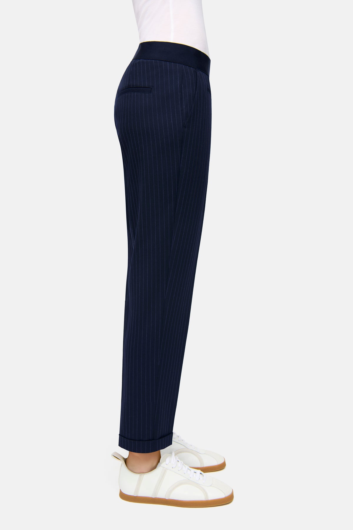 Dunkelblaue Nadelstreifenhose aus 62 % Polyester, 26 % Viskose, 9 % Wolle, 3 % Elasthan, getragen mit weißen Turnschuhen.