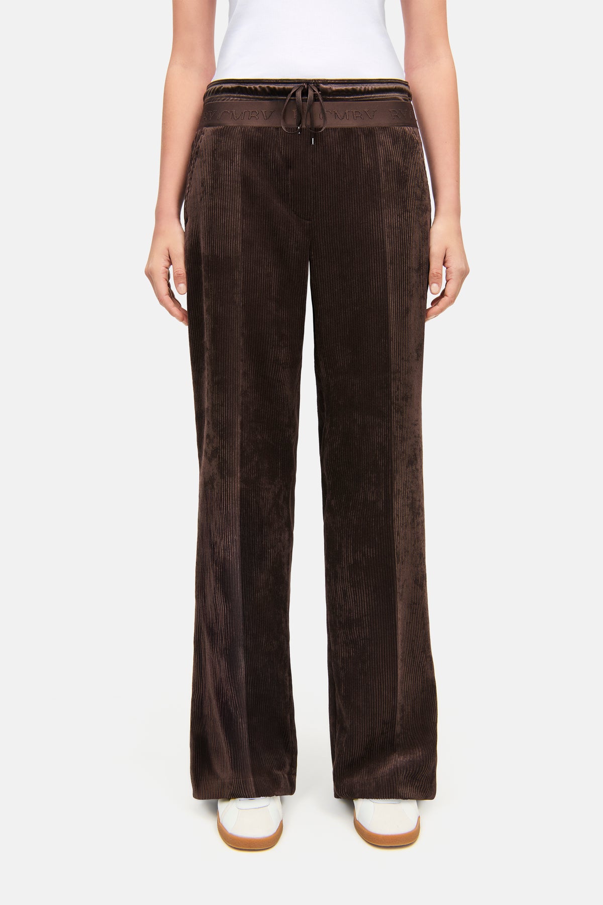 Braune, lang geschnittene Wide Leg Hose aus Breit-Cord Material mit Doppelbund und Schnürung, getragen in einer Casual-Umgebung.