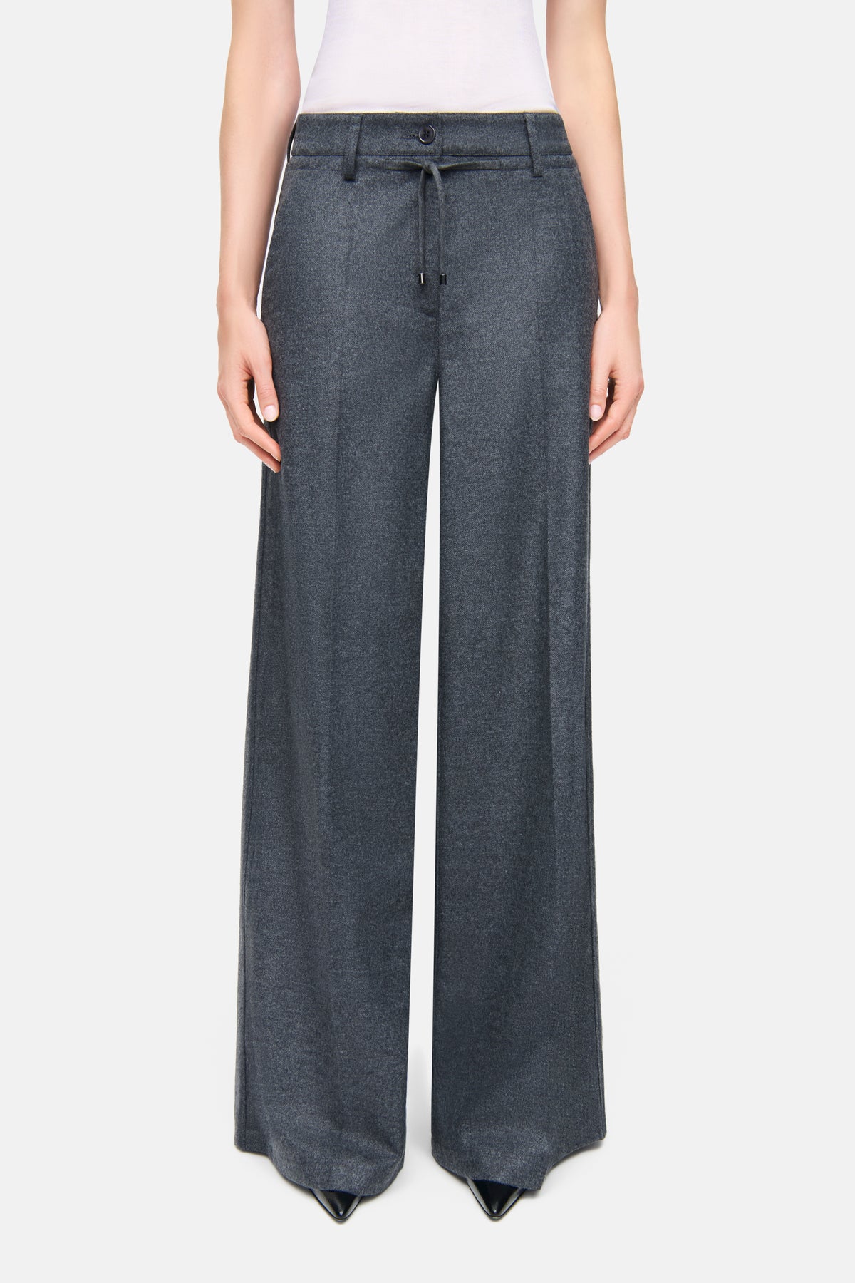 Graue Wide Leg Hose aus 55% Wolle, 45% Polyester, getragen in einem Innenraumszenario. Mit Knopfverschluss und Schnürung.