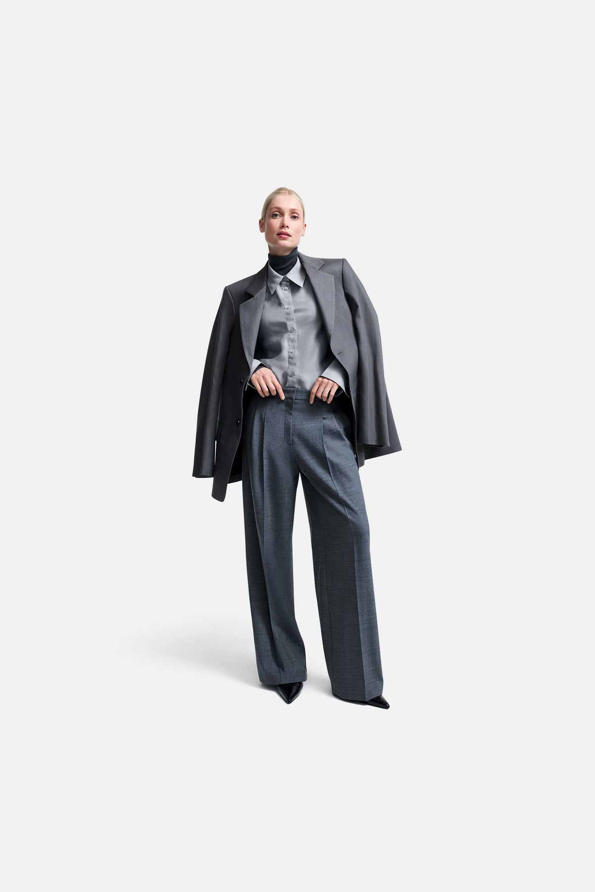 Graue Wide-Fit-Hose aus 53% Polyester, 43% Wolle, 4% Elasthan, getragen von einer Person in einem formellen Outfit.