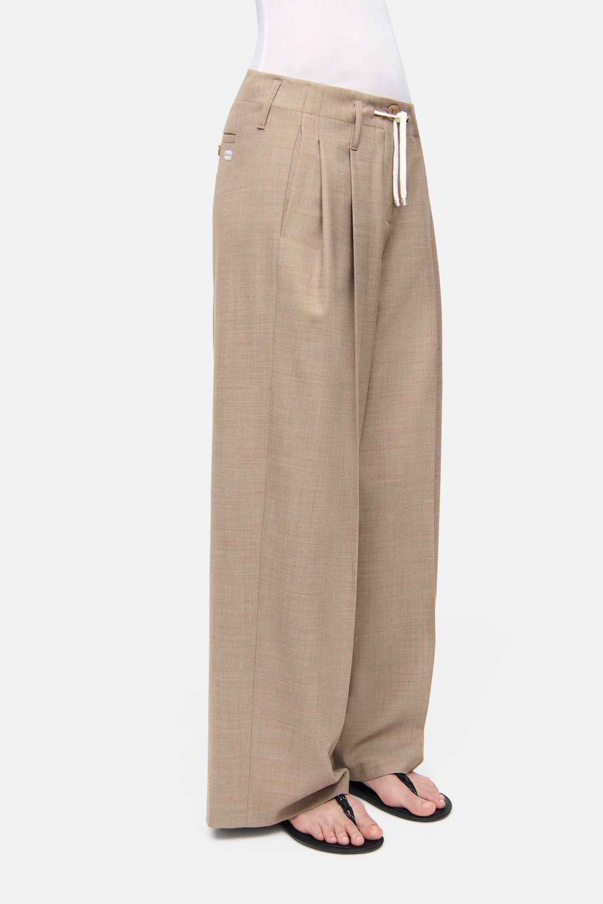 Weite, camel melierte Hose aus Wollmix-Gabardine, bestehend aus 53% Polyester, 43% Schurwolle und 4% Elasthan, getragen in einer entspannten Umgebung.