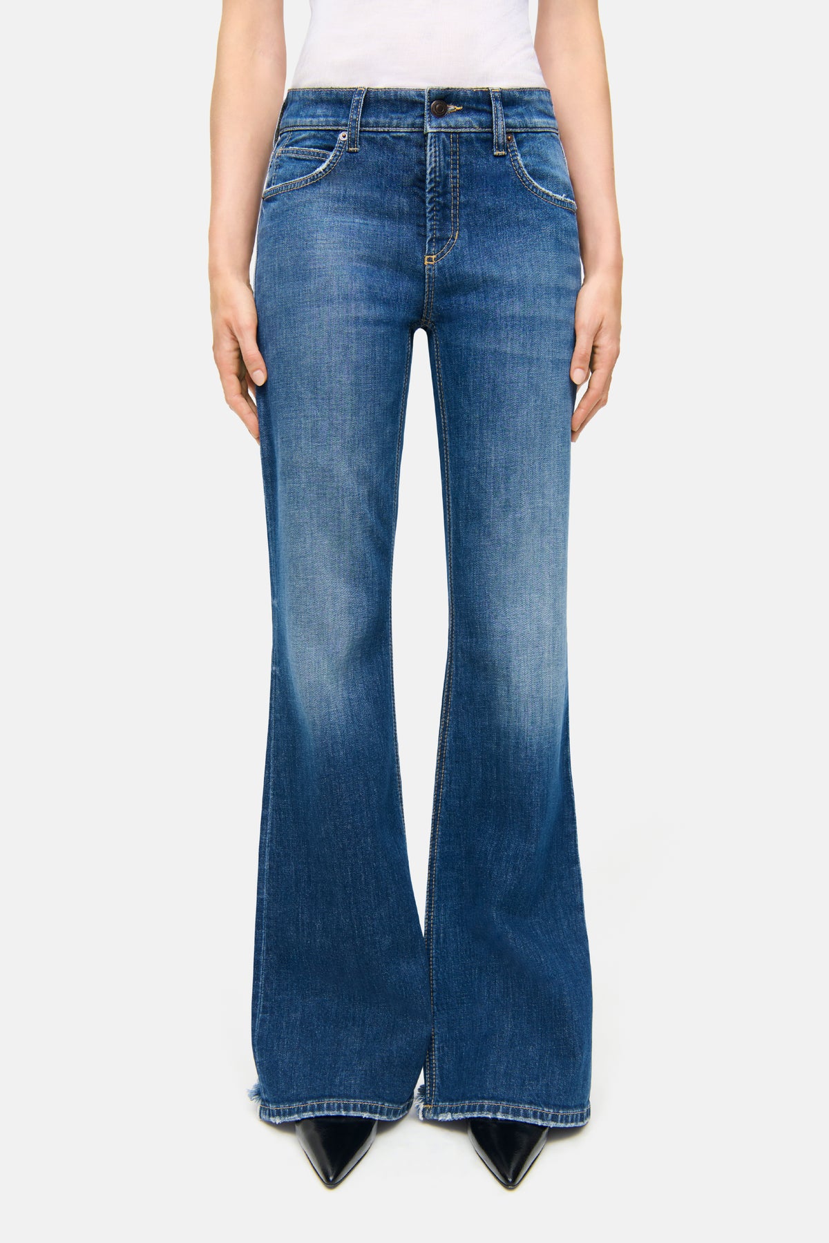 Blaue, ausgestellte Jeanshose aus 98% Baumwolle und 2% Elasthan. Wird in einem urbanen Umfeld getragen.