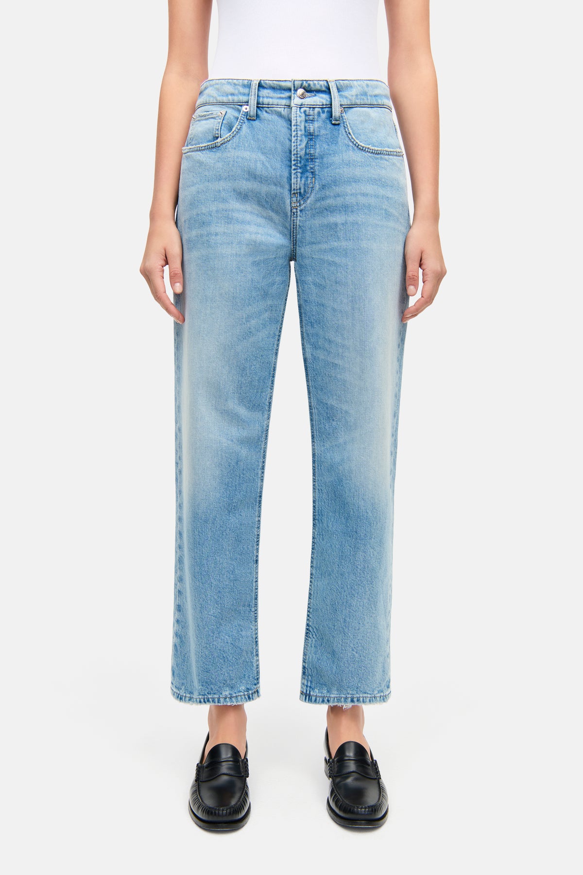Hellblaue Straight-Fit-Jeans, verkürzt, aus 98 % Baumwolle und 2 % Elasthan. Getragen in städtischem Umfeld.