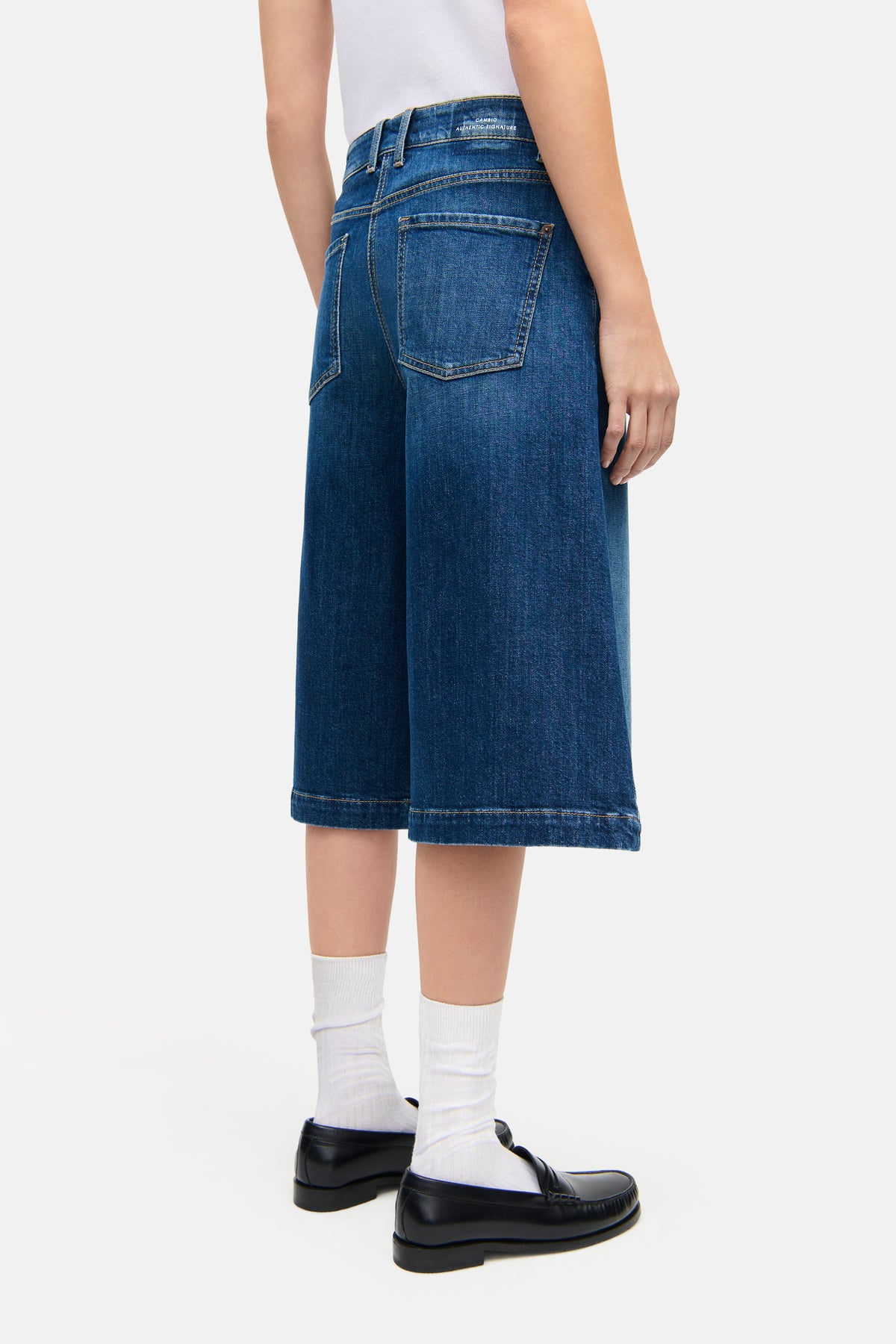 Blaue Bermuda-Jeans aus Denim, 98% Baumwolle, 2% Elasthan. Person trägt schwarze Schuhe und weiße Socken.