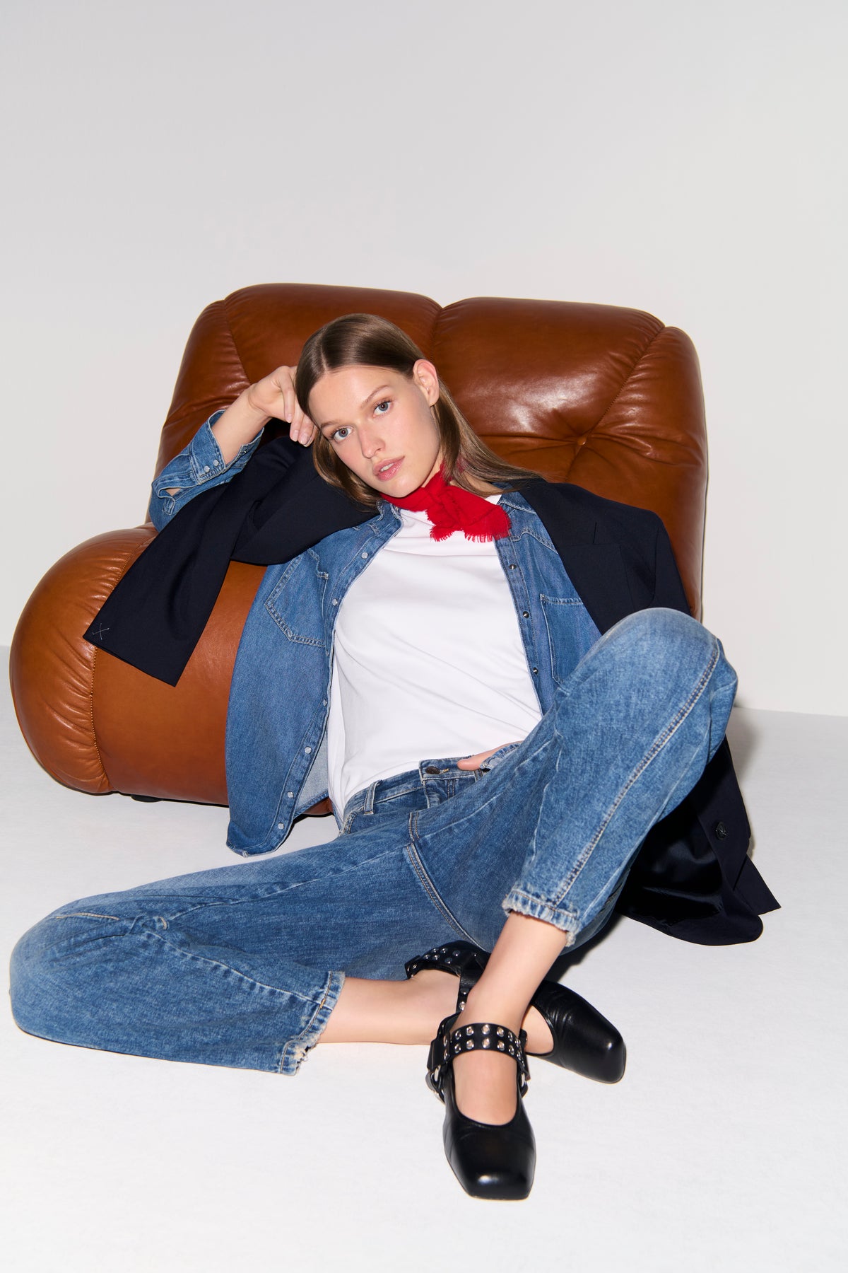 Frau sitzt in entspannter Pose auf einem braunen Sessel. Sie trägt eine O-Shape Denim Jeans in Blau aus 98% Baumwolle und 2% Elasthan.