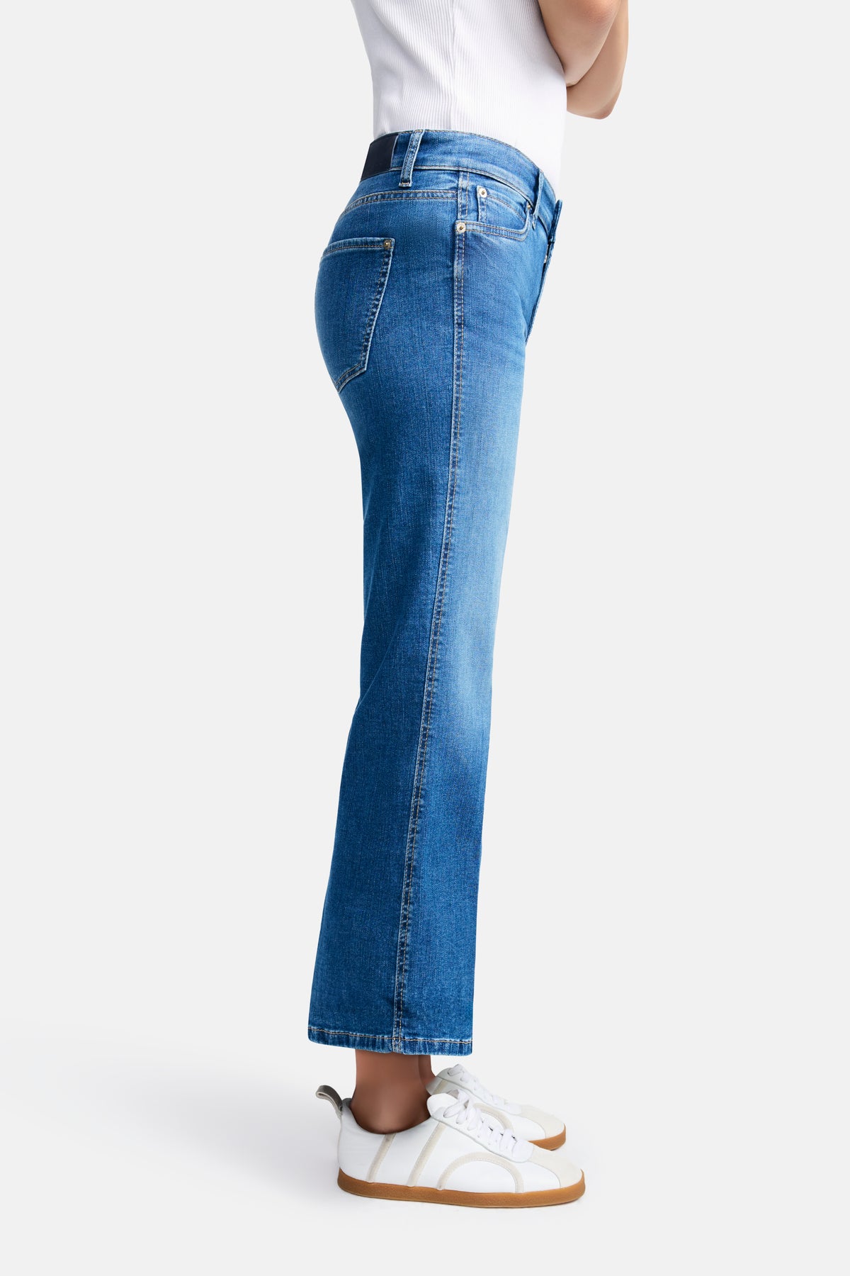 Hellblaue Flared Jeans aus 92% Baumwolle, 6% Elastomultiester T400 und 2% Elasthan. Person steht auf weißem Hintergrund.