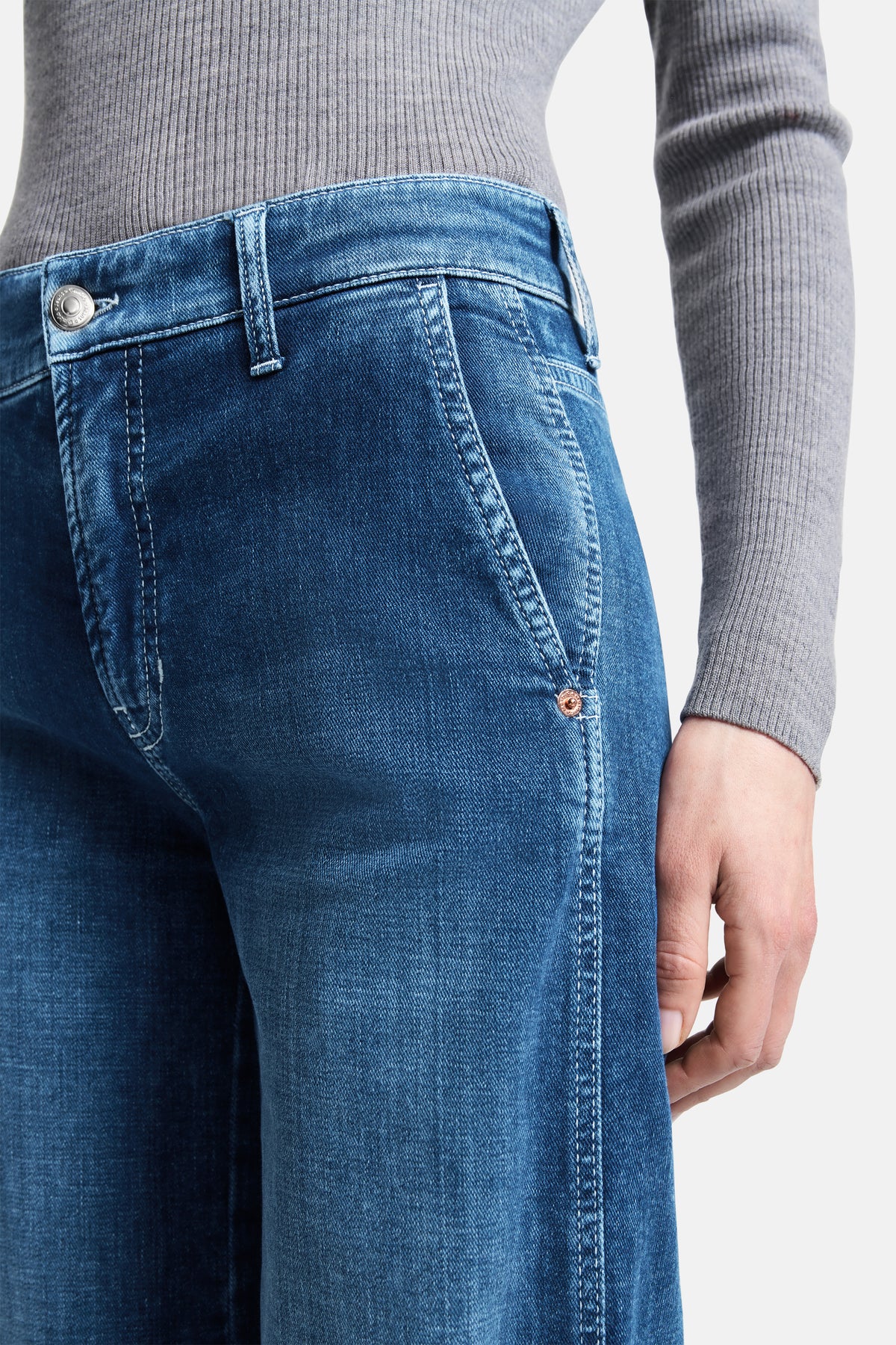 Person trägt blaue Wide-Leg-Jeans aus 92 % Baumwolle, 6 % Elastomultiester und 2 % Elasthan, in urbanem Setting.