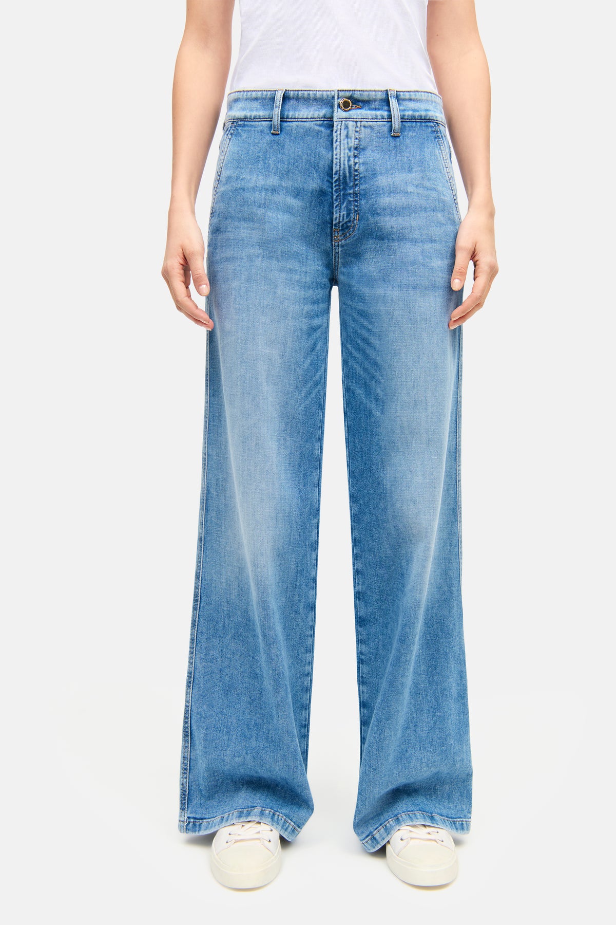 Weite, lange Jeans aus hellem Blau, Material: 92% Baumwolle, 6% Elastomultiester T400, 2% Elasthan. Getragen mit weißen Sneakern.
