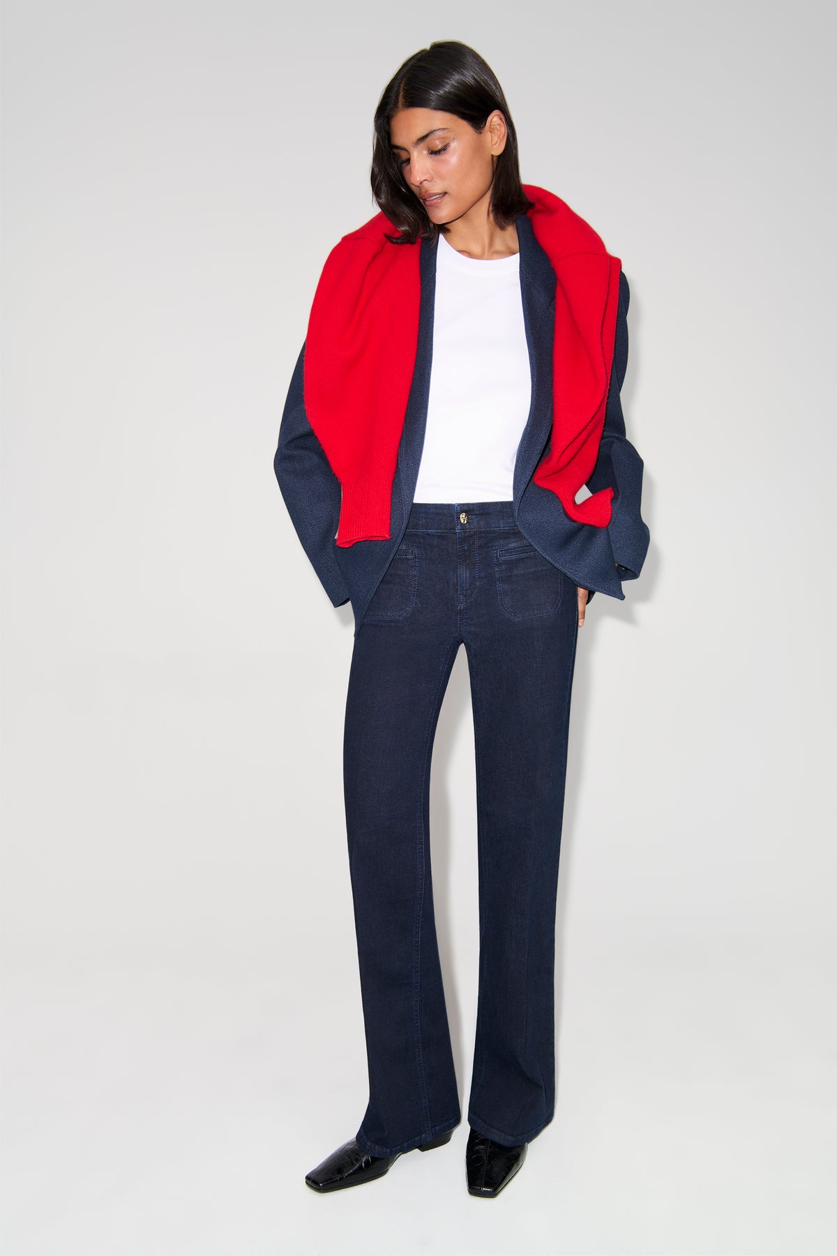 Dunkelblaue Wide-Leg-Jeans aus 93% Baumwolle, 5% Polyester, 2% Elasthan. Szenario: Person trägt die Hose mit rotem Schal.