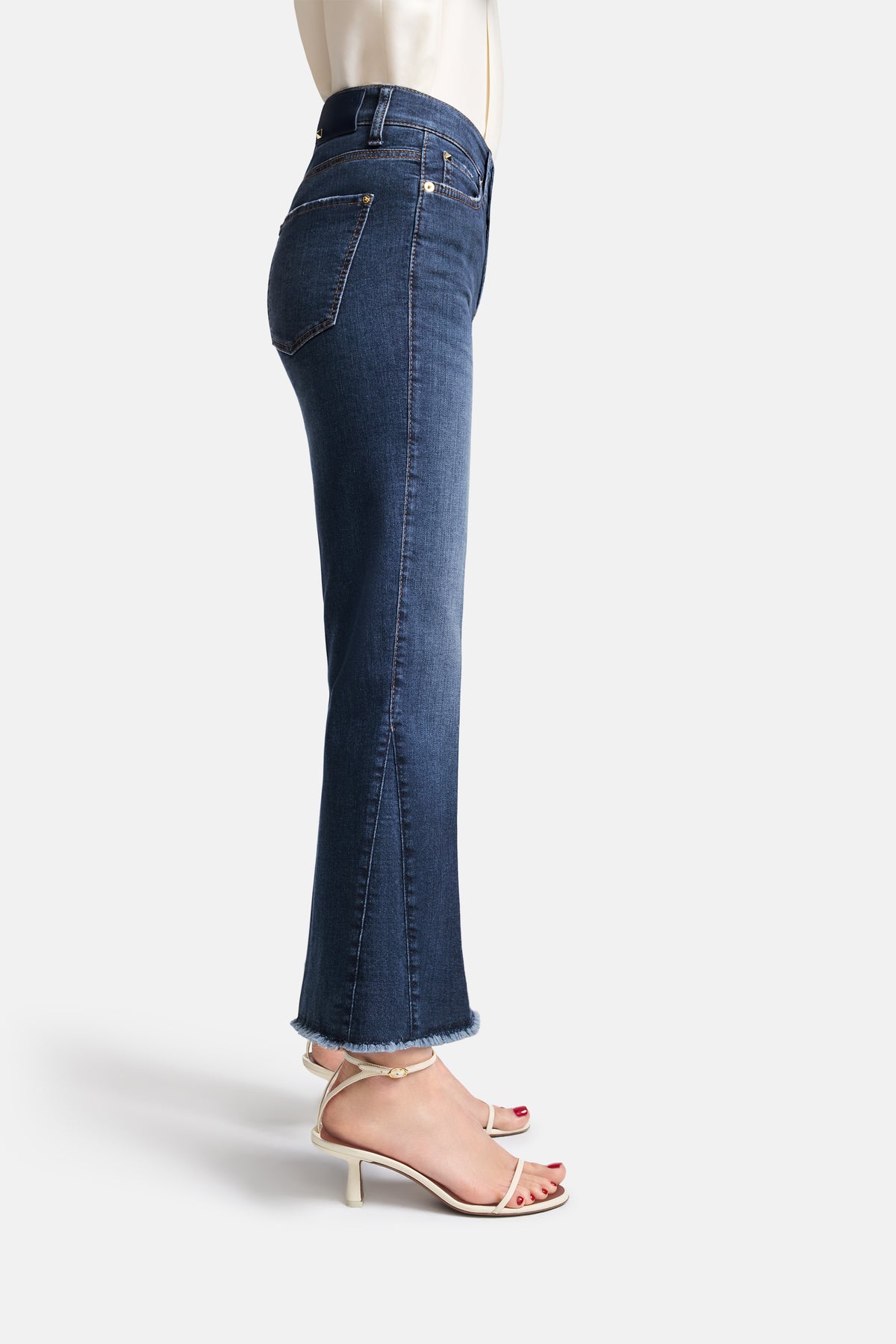 Blaue, verkürzte Flared Jeans aus 92% Baumwolle, 6% Elastomultiester T400, 2% Elasthan. Getragen mit weißen Sandalen.