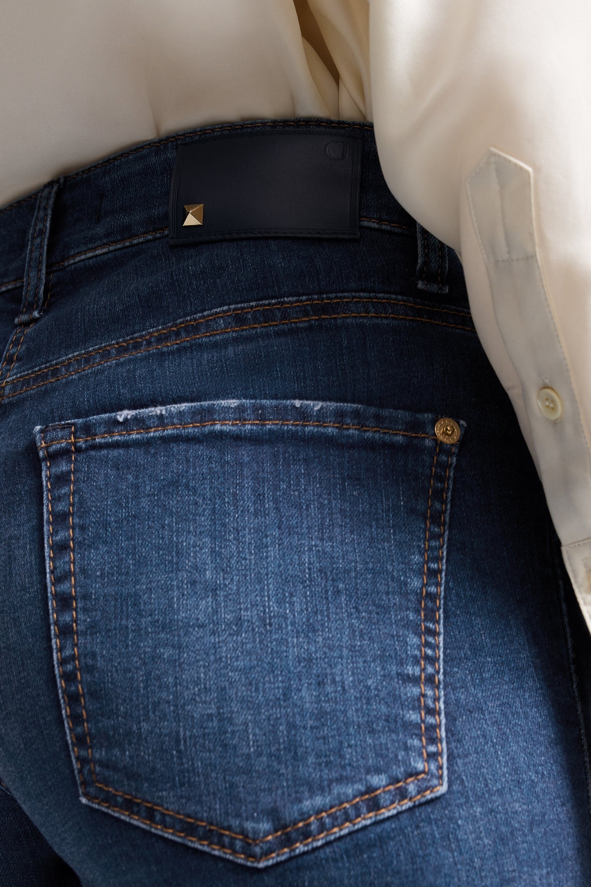 Blaue, verkürzte Flared Jeans aus 92% Baumwolle, 6% Elastomultiester, 2% Elasthan, getragen von einer Person in Innenraum.