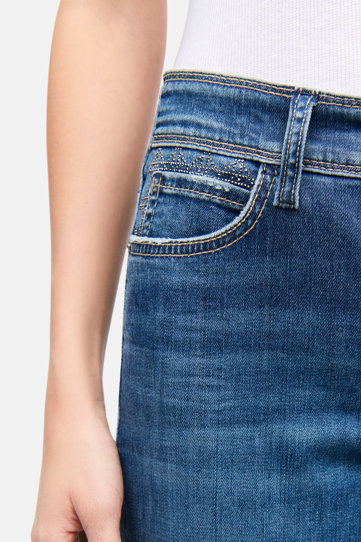 Blaue Slim-Fit Jeans aus 92% Baumwolle, 6% Elastomultiester T400, 2% Elasthan. Strass-Details an der Vordertasche sichtbar.