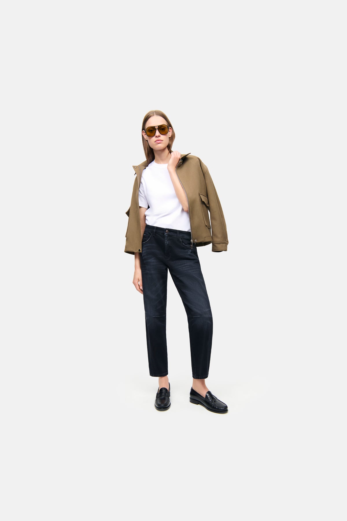 Schwarze O-Shape-Jeans aus 57% Baumwolle, 37% Modal, 4% Elastomultiester T400, 2% Elasthan. Kontext: Frau trägt Sonnenbrille und Jacke.