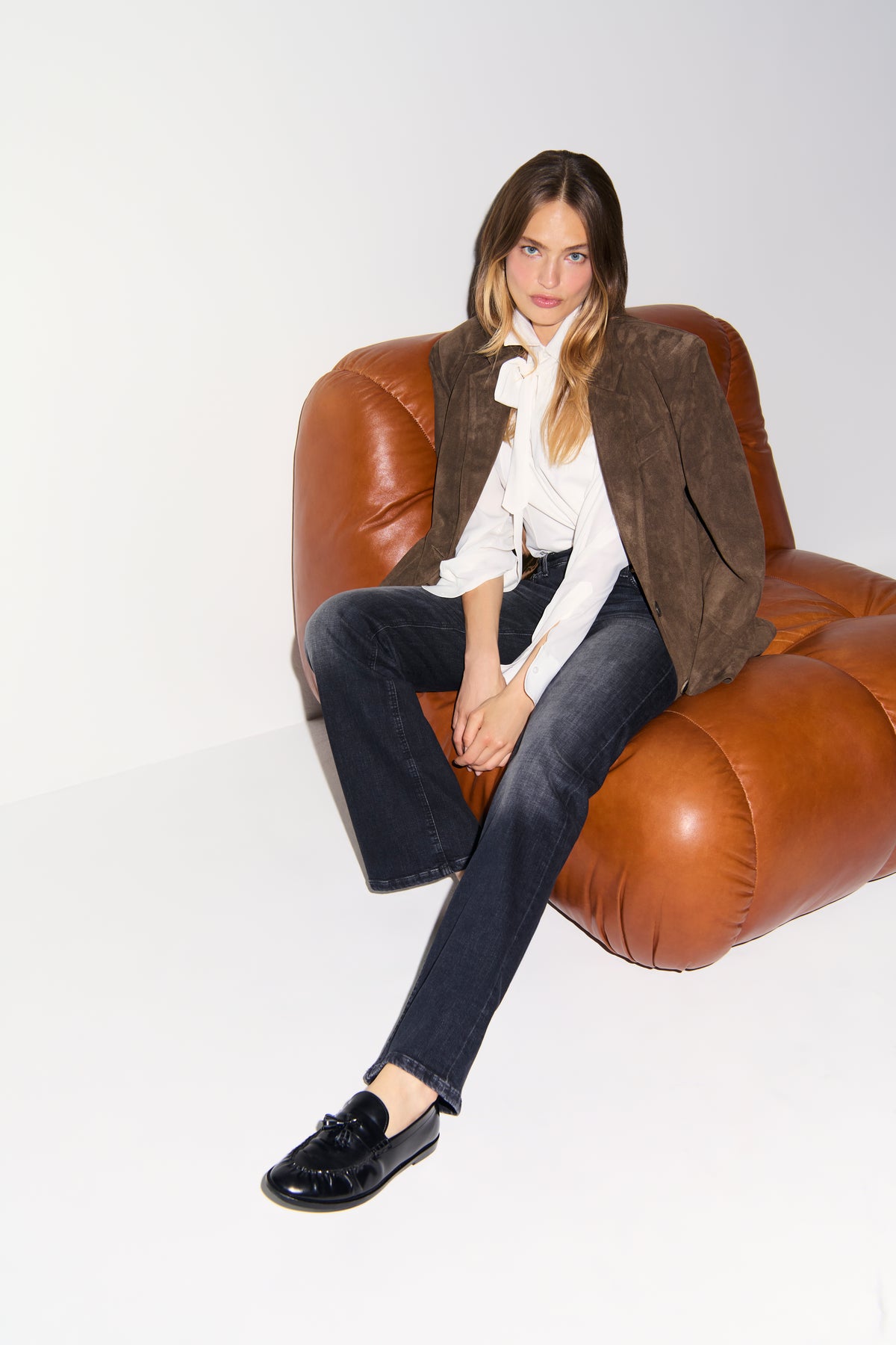 Dunkle Wide-Leg Denim-Hose, 97% Baumwolle und 3% Elasthan, in einem stilvollen, modernen Setting mit Ledersessel.