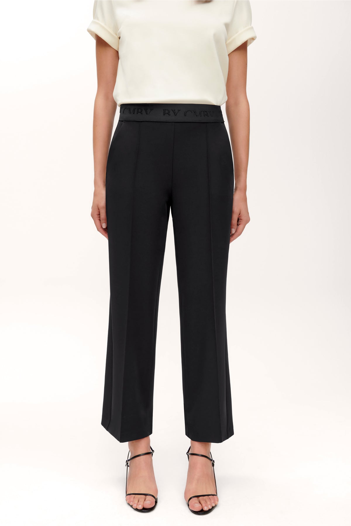 Schwarze Culotte-Hose im Wide-Fit, gefertigt aus 92% Polyester und 8% Polyurethan, mit elastischem Bund. Frau steht.