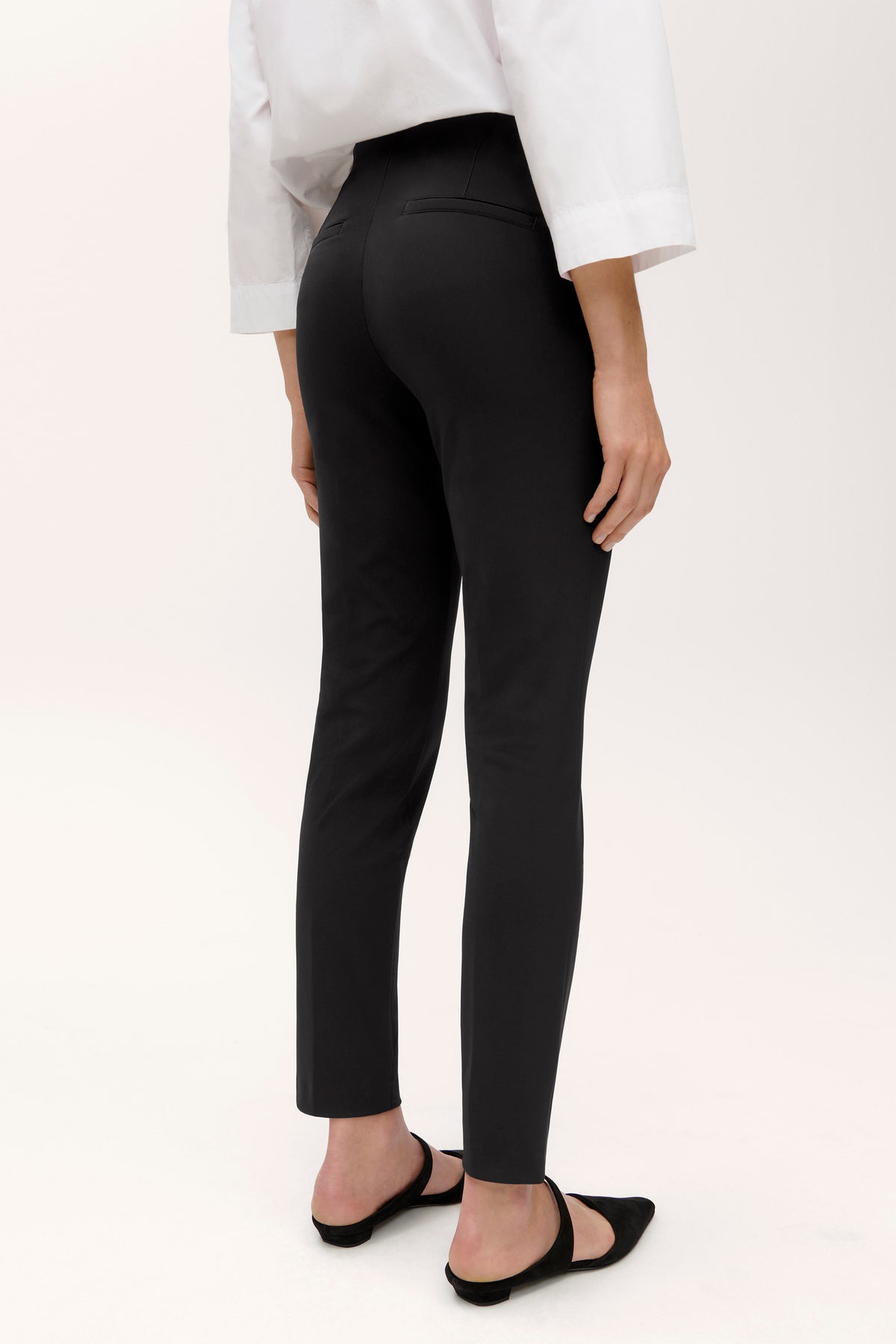 Schwarze Slim-Fit-Hose aus 88 % Polyamid und 12 % Elasthan, getragen von einer Person in einem schlichten, weißen Hemd.
