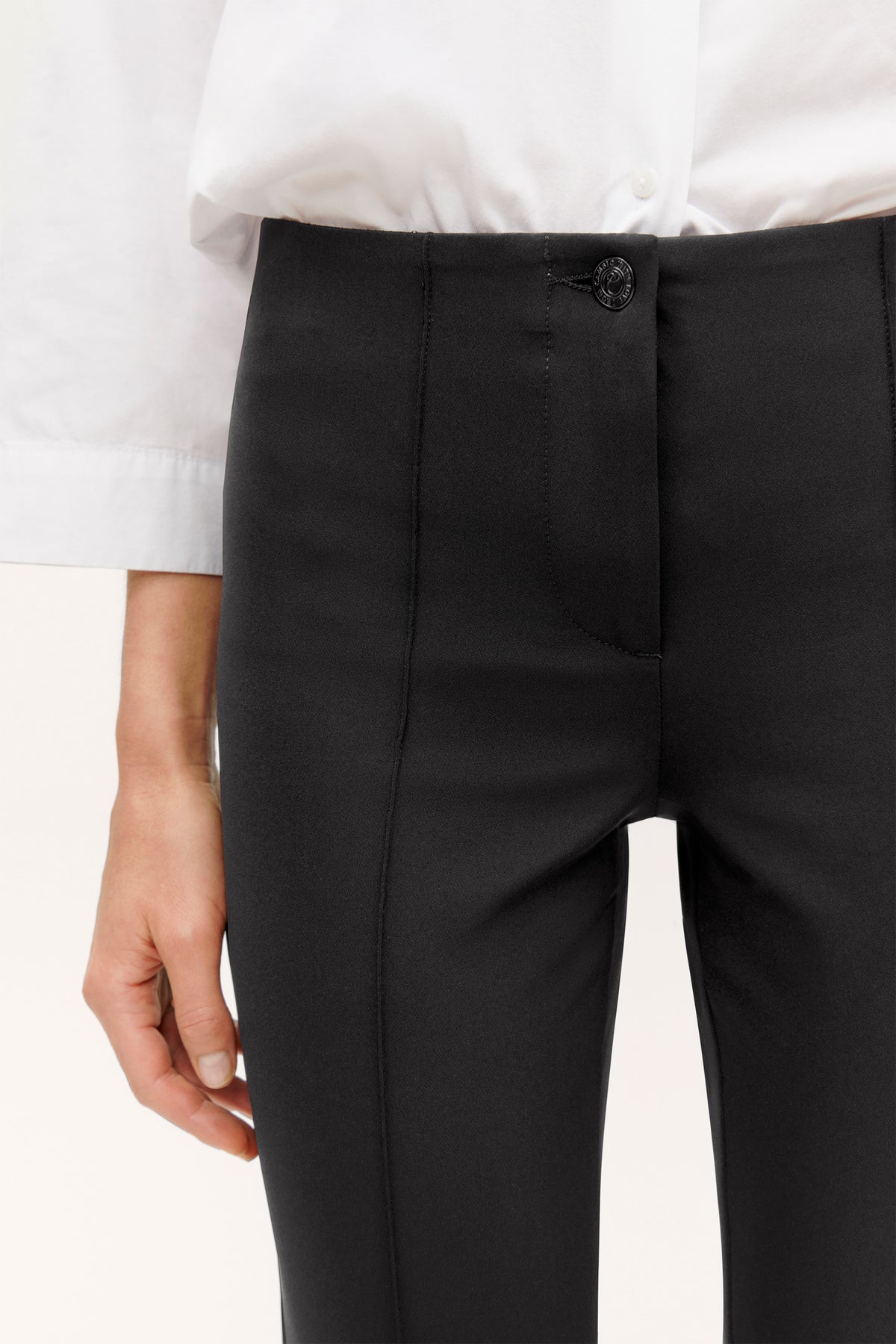 Schwarze Slim-Fit Hose aus 88% Polyamid und 12% Elasthan, getragen in einem Bürokontext mit weißer Bluse.