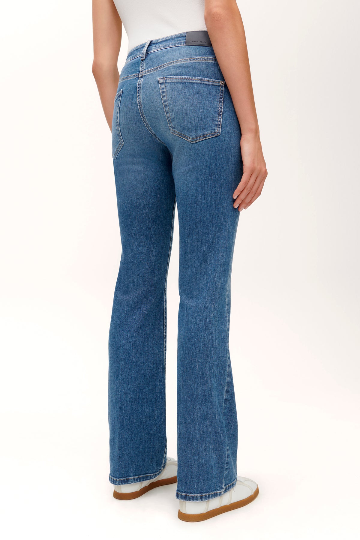 Blaue Flared-Jeans aus 92 % Baumwolle, 6 % Elastomultiester T400, 2 % Elasthan, getragen von einer Person in einem casual Setting.
