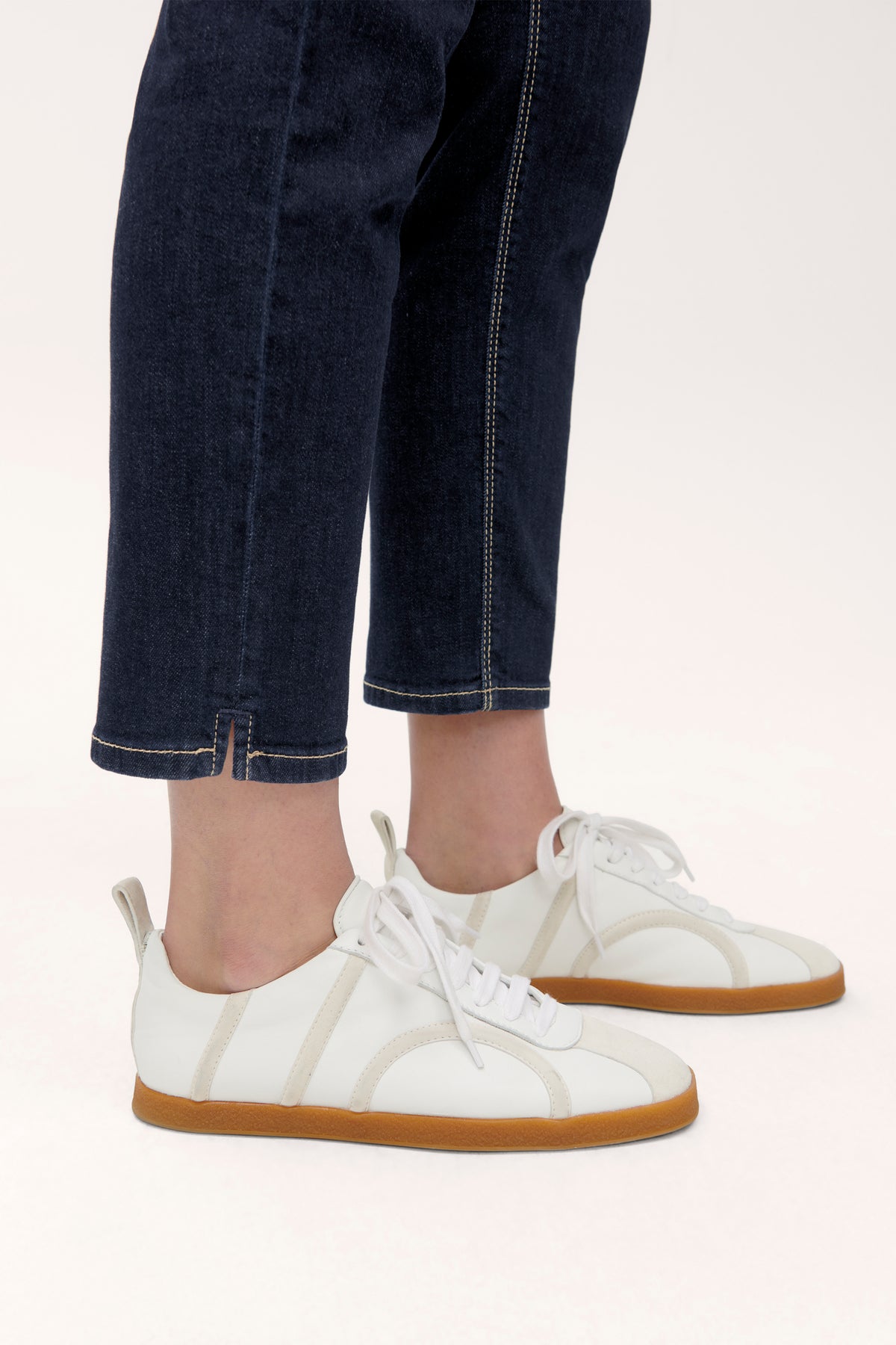 Blaue, schmal geschnittene Jeanshose aus 93% Baumwolle, 5% Polyester und 2% Elasthan. Getragen mit weißen Sneakern.