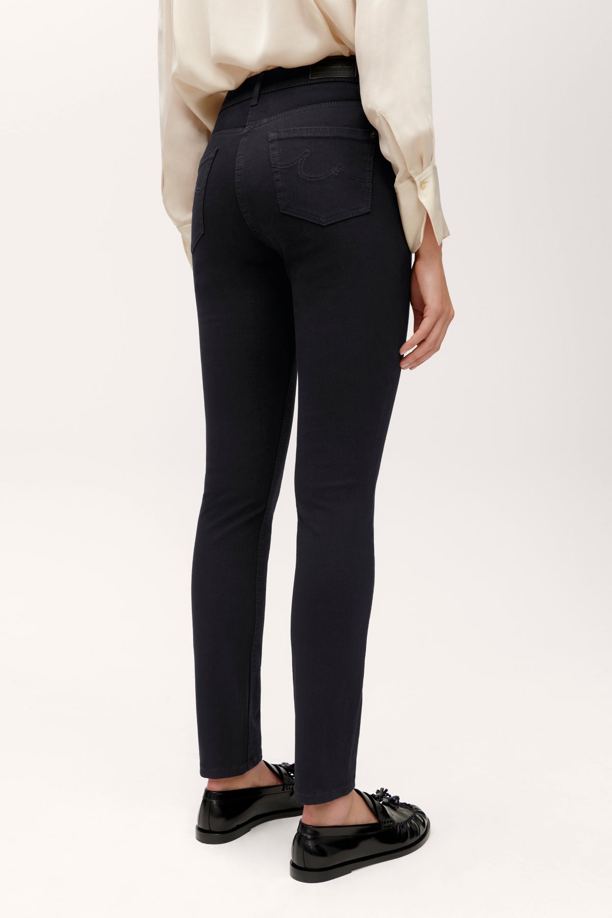 Schwarze Slim-Fit-Jeans aus 77% Baumwolle, 18% Polybutylenterephthalat, 5% Elasthan. Person steht in neutralem Kontext.