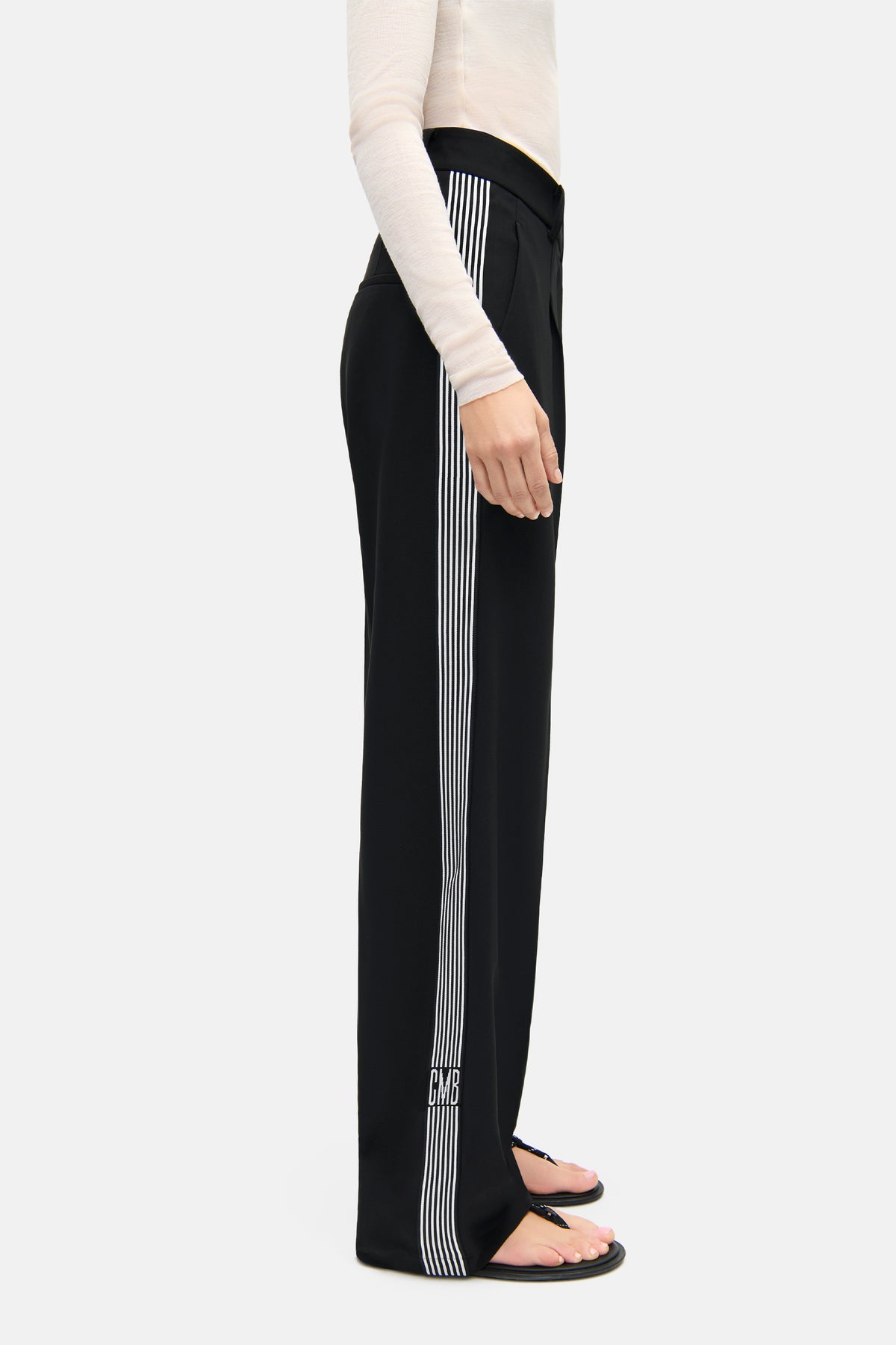 Schwarze O-Shape Hose aus 92% Polyester und 8% Polyurethan mit Galonstreifen und CMB Logo. Indoor-Szene, Frau trägt die Hose.