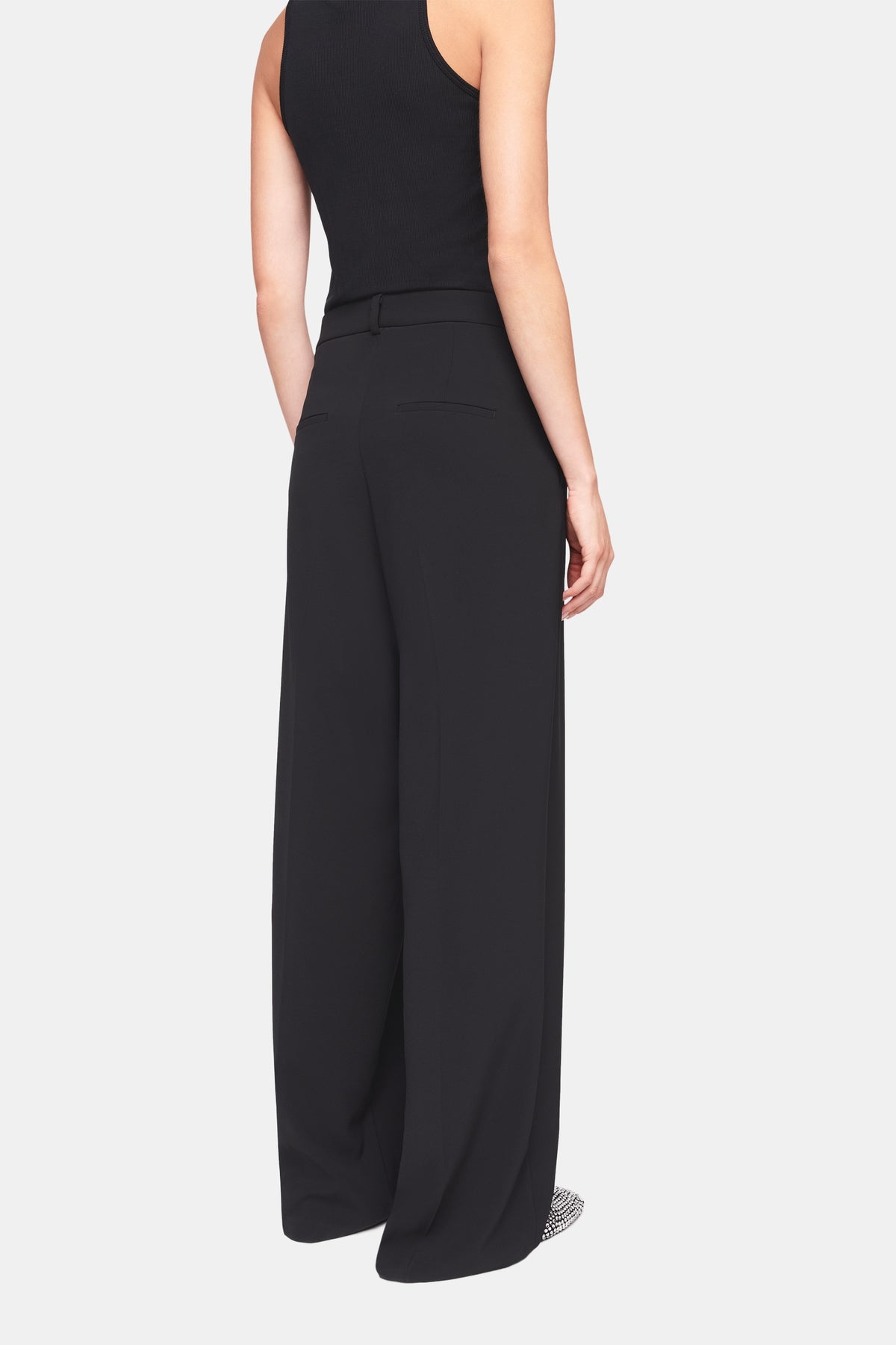 Schwarze, weit geschnittene Hose aus 90% Polyester und 10% Polyurethan. Getragen von einer Person in einem Studio-Setting.