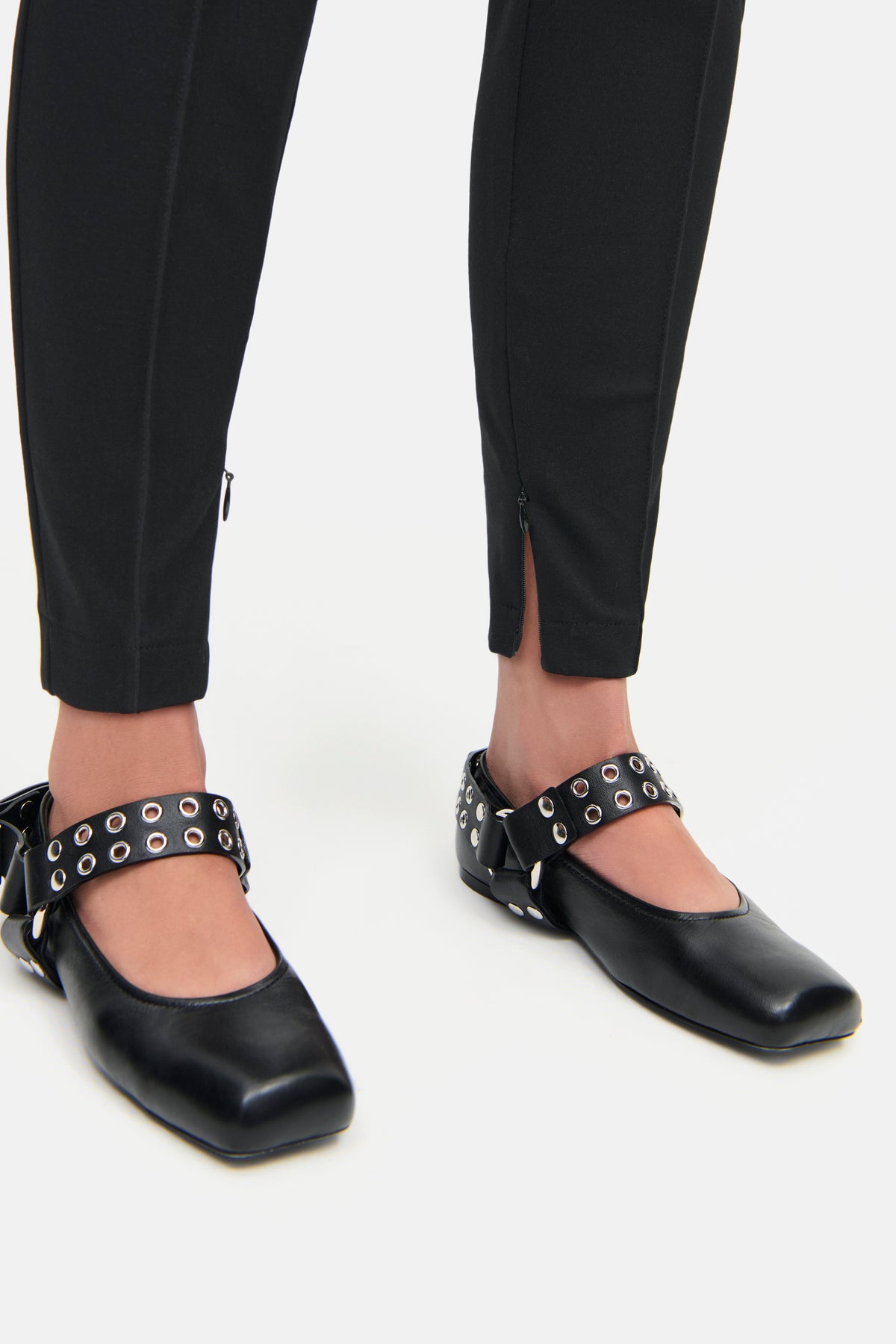 Schwarze Skinny-Fit-Hose aus 61% Viskose, 25% Polyamid, 14% Elasthan, mit seitlichem Reißverschluss am Saum getragen von einer Person, kombiniert mit schwarzen Schuhen.