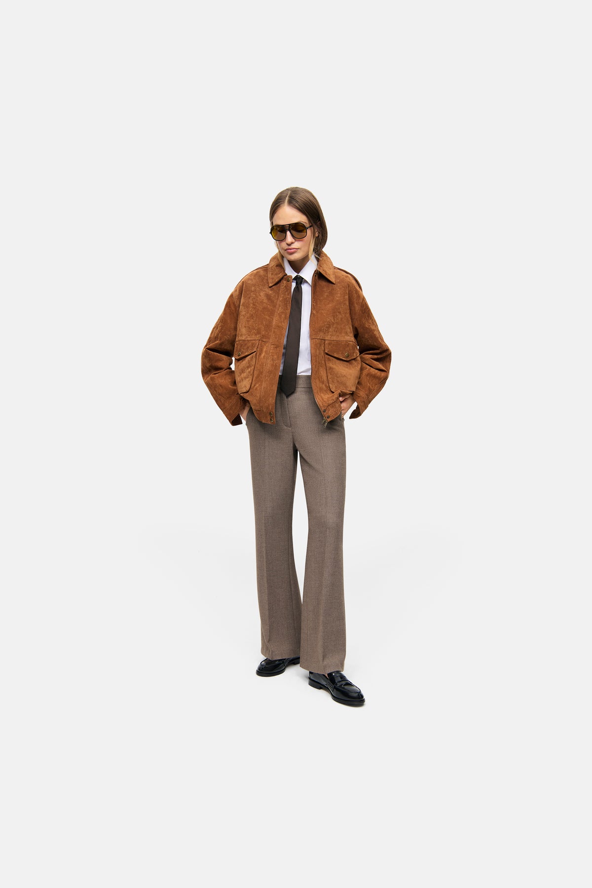 Damen trägt beige weite Hose, Anzugstil, Materialmix aus Polyester, Viskose, Wolle und Elasthan. Büro-Umgebung.