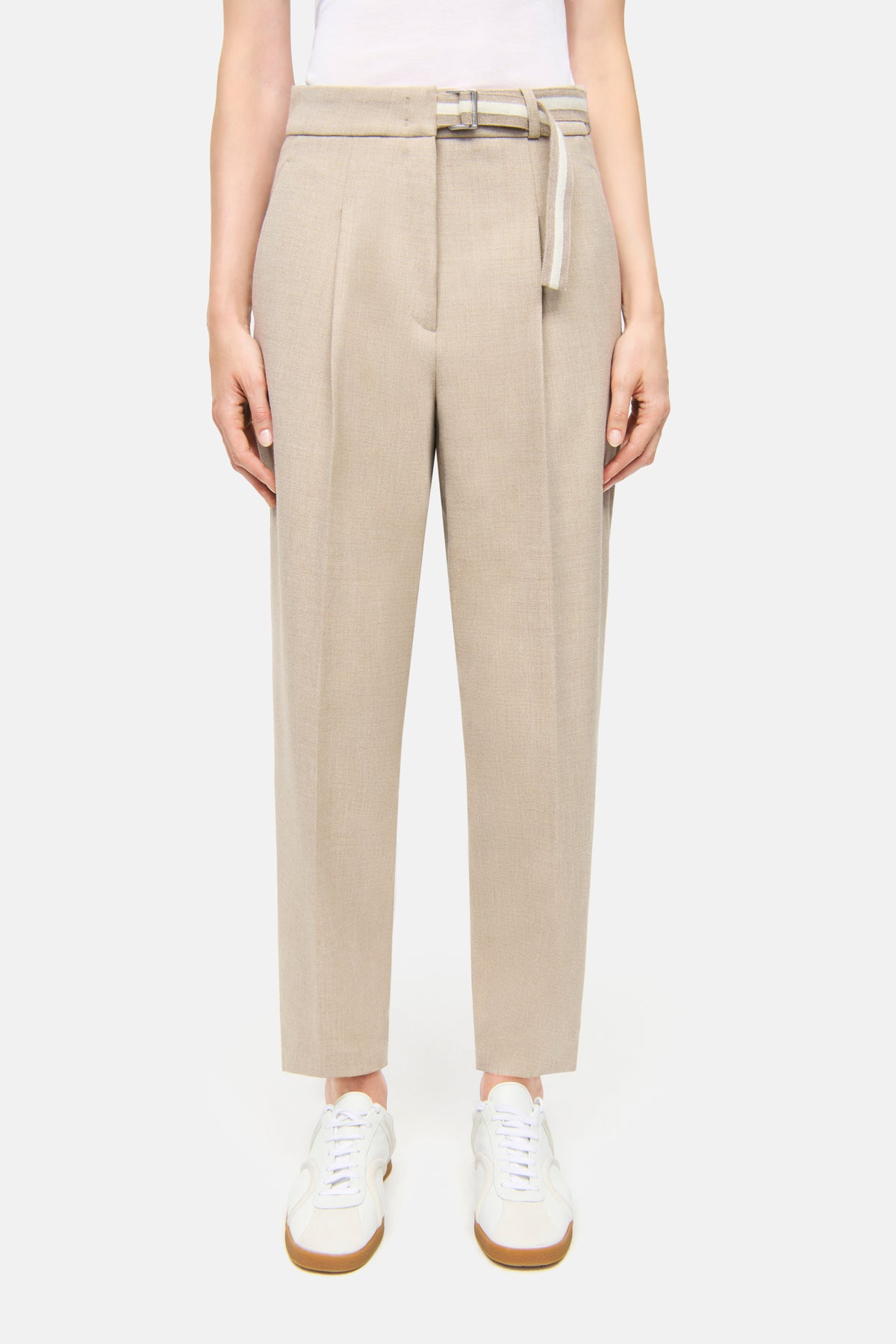 Beige O-Shape Hose mit Bundfalte aus 62% Polyester, 26% Viskose, 9% Wolle, 3% Elasthan. Person trägt sie mit weißen Sneakers.