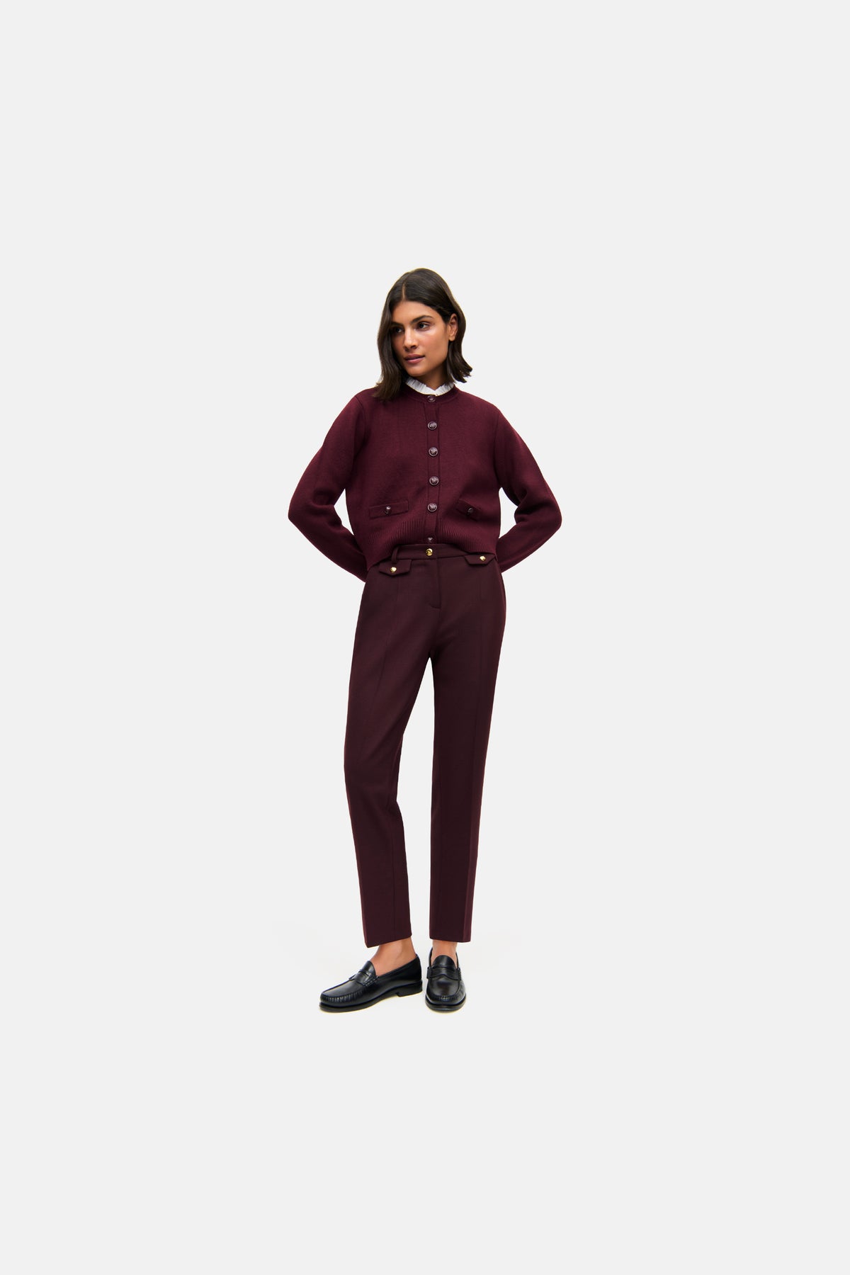 Bordeauxfarbene Karottenhose aus 62 % Polyester, 26 % Viskose, 9 % Wolle und 3 % Elasthan. Frau im lässigen Outfit.