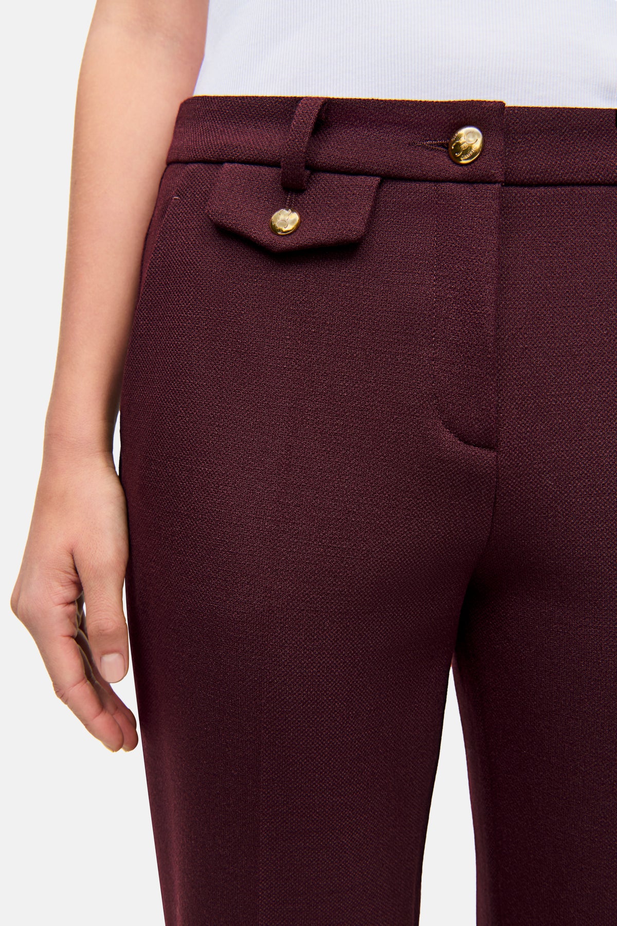 Weinrote Karottenhose aus 62% Polyester, 26% Viskose, 9% Wolle, 3% Elasthan mit goldenen Knöpfen.