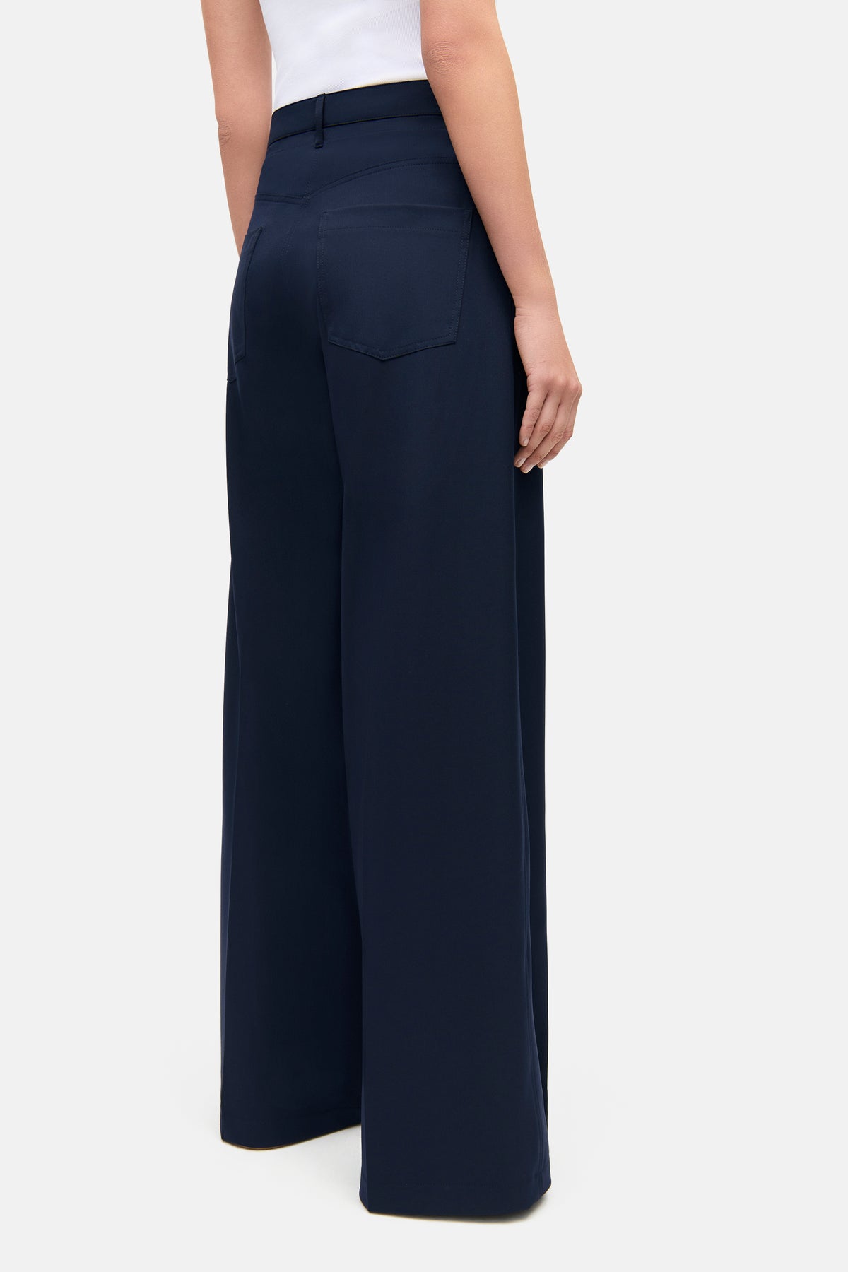 Dunkelblaue Wide-Leg-Hose aus 67% Polyester, 4% Elasthan und 29% Viskose, getragen von einer Person im Innenraum.