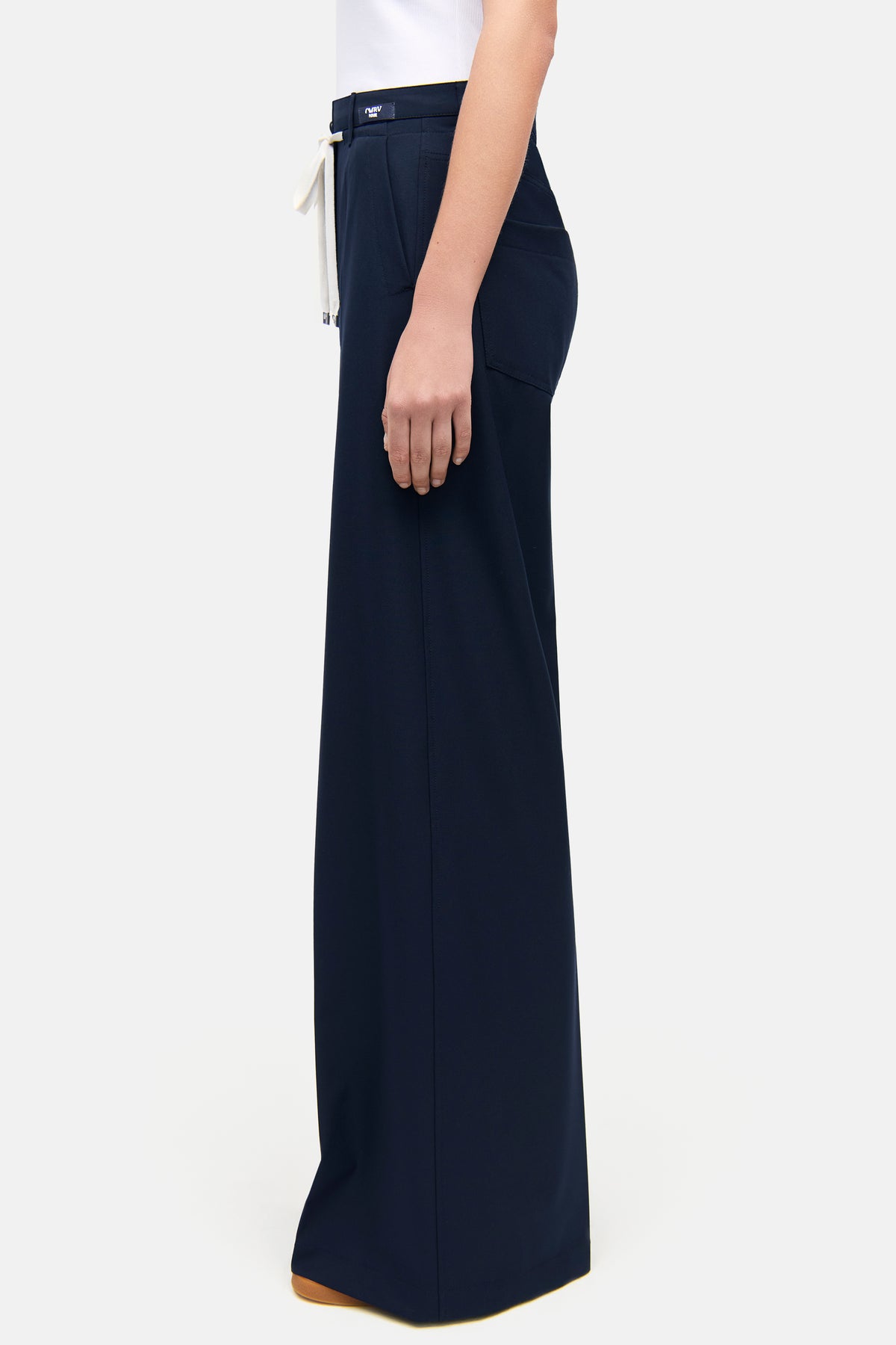 Dunkelblaue, weite Hose aus 67% Polyester, 29% Viskose, 4% Elasthan. Seitliche Eingrifftaschen, von Person im Innenraum getragen.