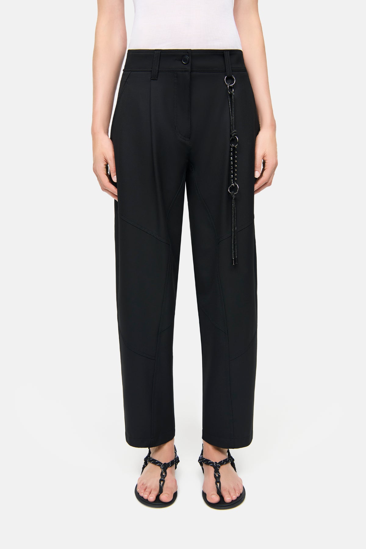 Schwarze O-Shape Hose aus 67% Polyester, 29% Viskose, 4% Elasthan. Getragen von einer Person mit Sandalen. Im Innenraum.