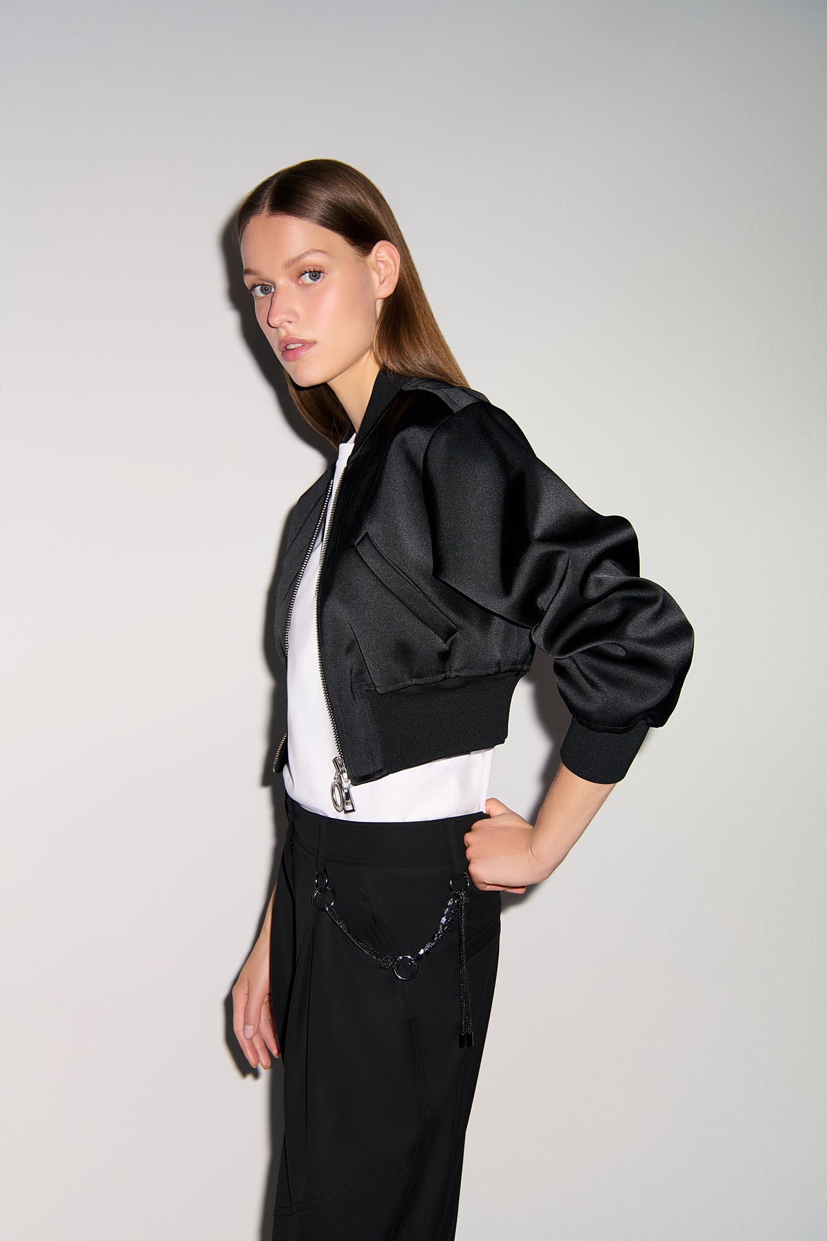 Schwarze O-Shape Hose aus 67% Polyester, 29% Viskose, 4% Elasthan, getragen mit einer abnehmbaren Charivari-Kette. Indoor-Setting.