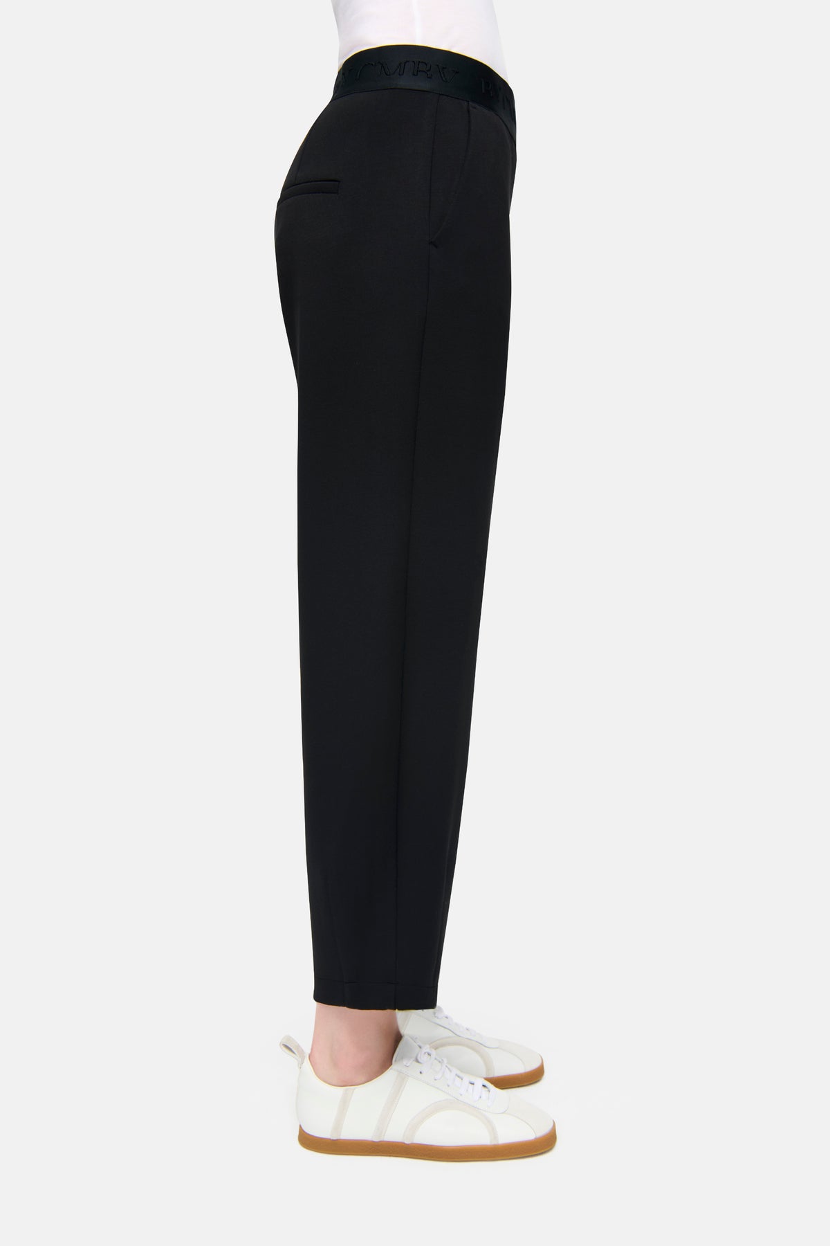 Schwarze O-Shape Hose aus Neopren, bestehend aus 47% Polyamid, 44% Viskose, 9% Elasthan, mit elastischem Bund. Im Casual-Setting getragen, kombiniert mit weißen Sneakers. Angenehme Passform dank elastischem CMB-Bund, seitliche Taschen vorhanden.