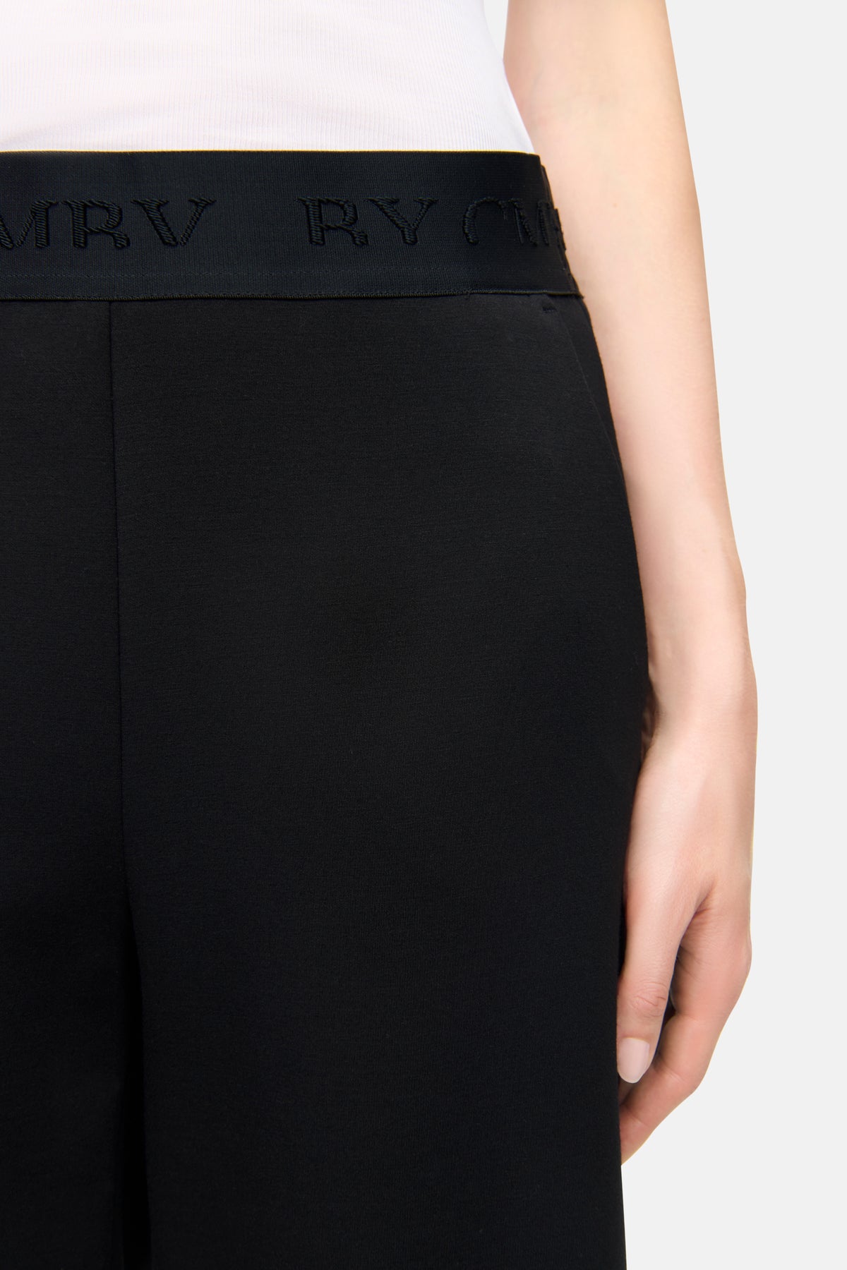 Schwarze O-Shape Hose aus Neopren mit elastischem Bund und "CMB"-Wording, seitliche Taschen, Material aus Polyamid, Viskose, Elasthan. Getragen in privatem Umfeld.